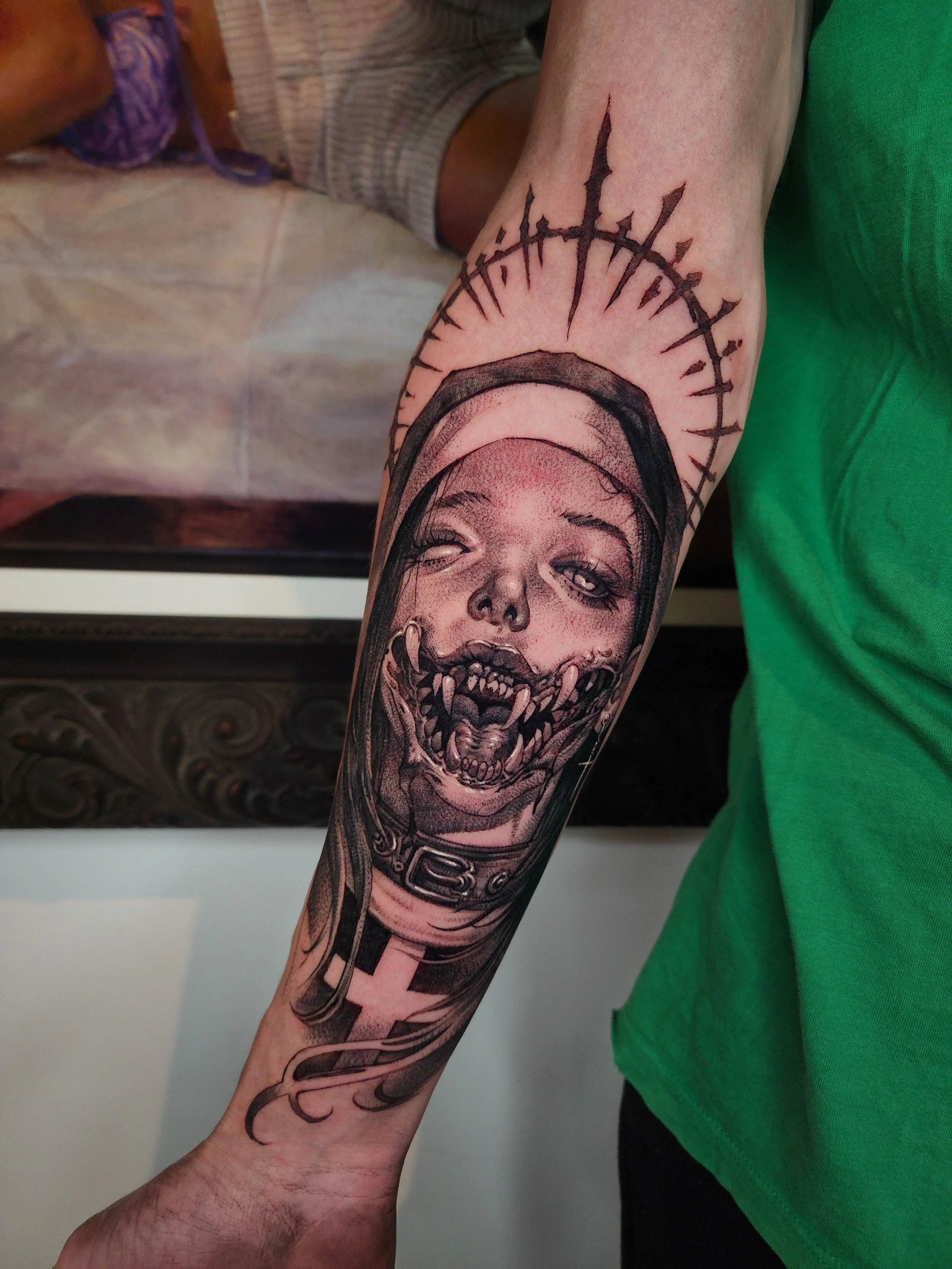 A tattoo on a person's arm featuring a realistic portrait of a woman with a crown of thorns above her head, a dog collar around her neck, and an aggressive, snarling expression with sharp teeth.