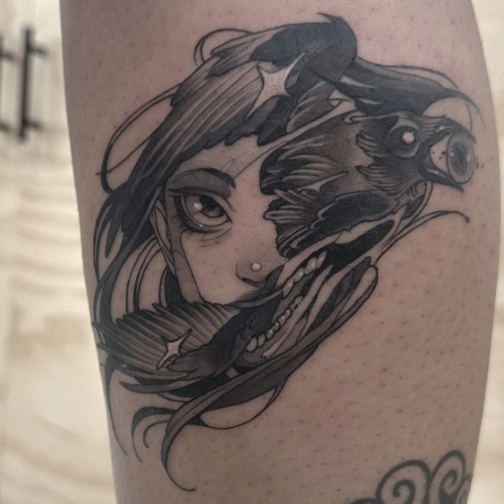Tattoo of a woman's face with long flowing hair and a roaring lion's face intertwined, in black ink.