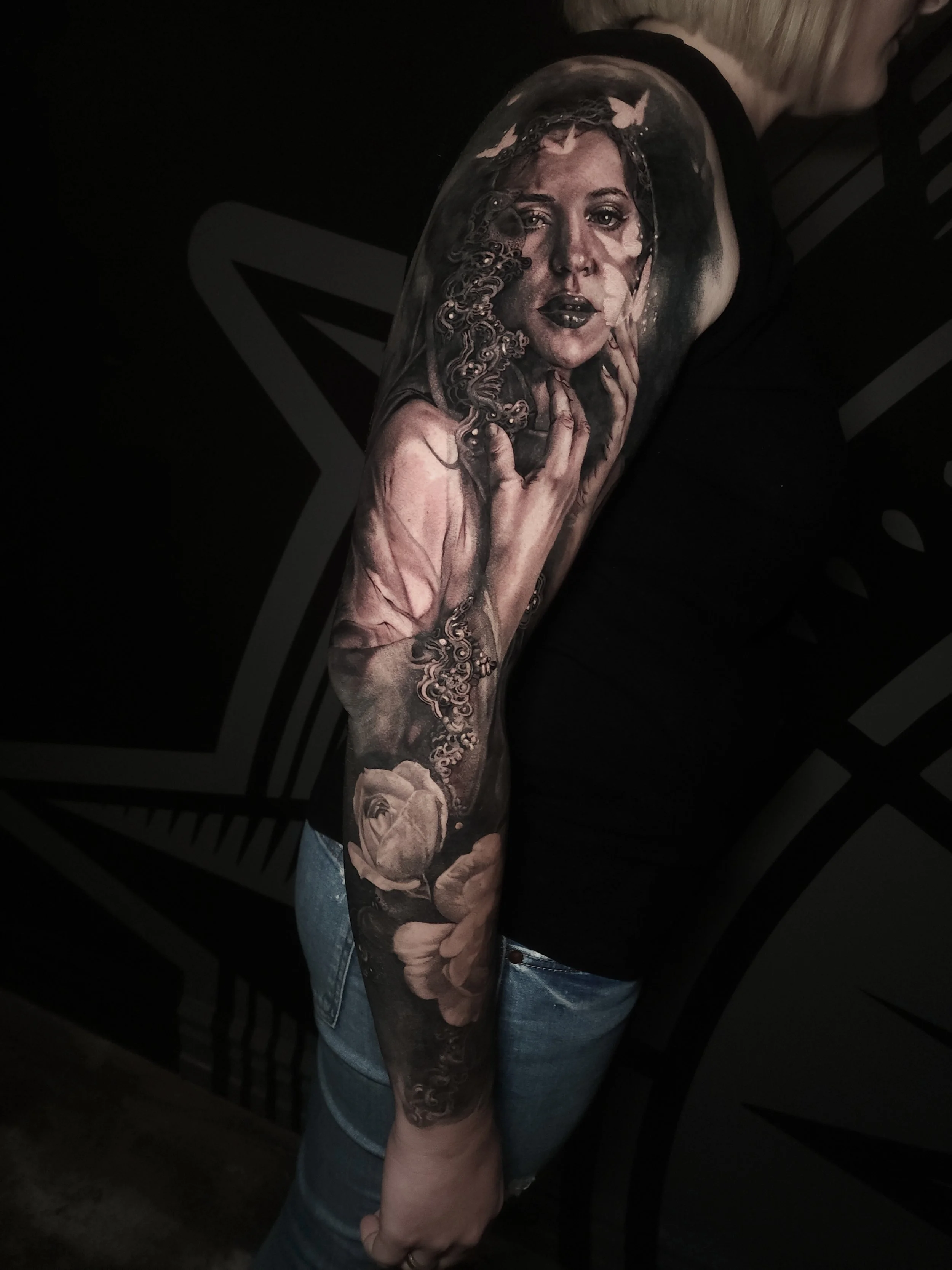 Tattoo of a woman's face with butterflies and roses on forearm