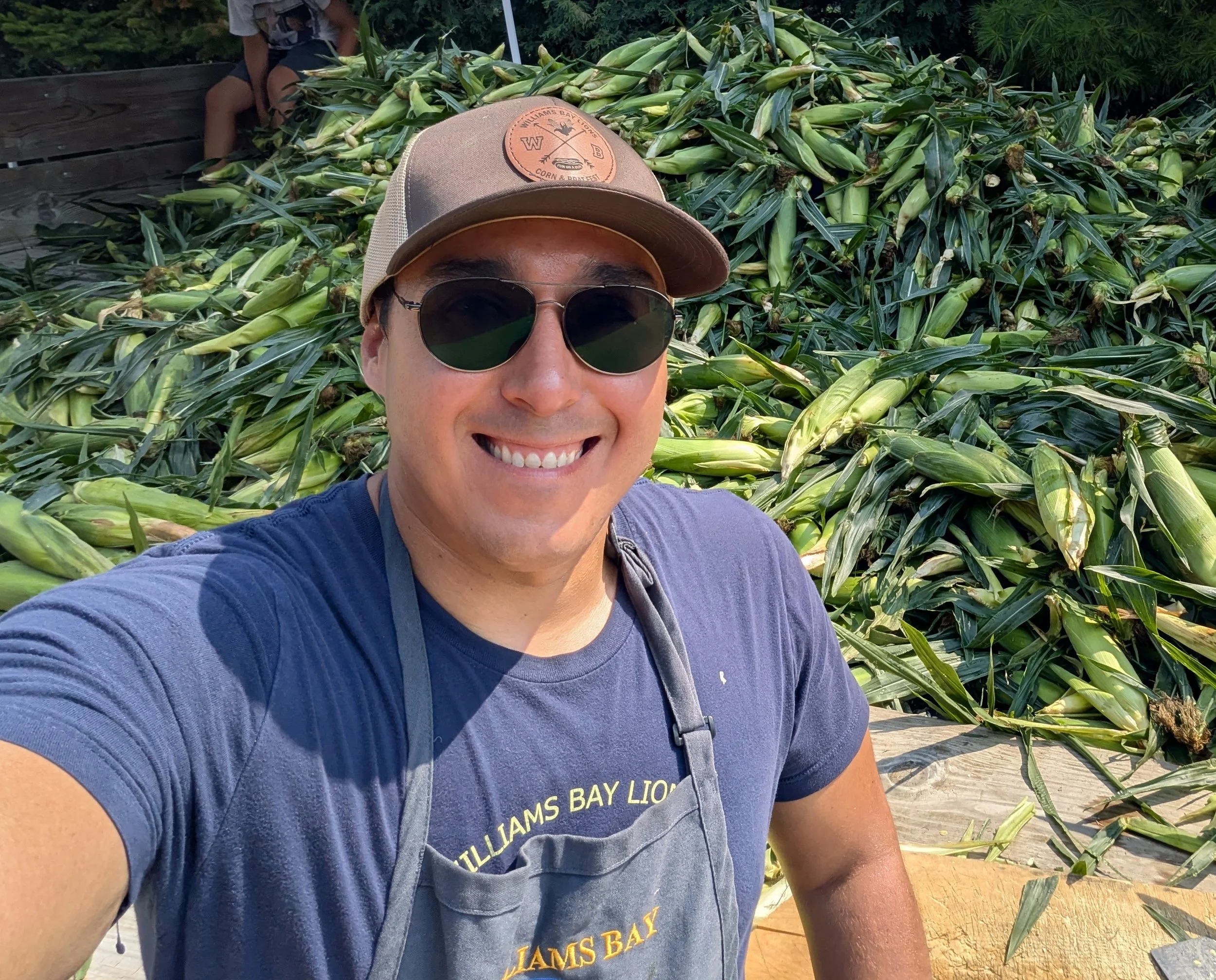 Adam shucking corn as a Williams Bay Lions Club volunteer during the annual Corn and Brat Fest