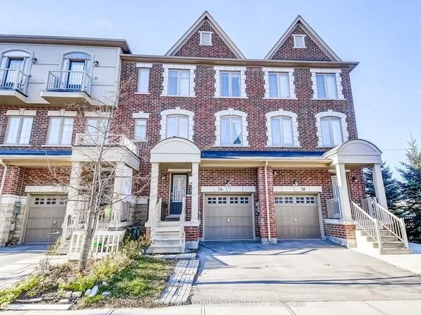 Three-story brick townhouse with three garages, stairs on each side leading to the front doors, and a tree with leafless branches in front.