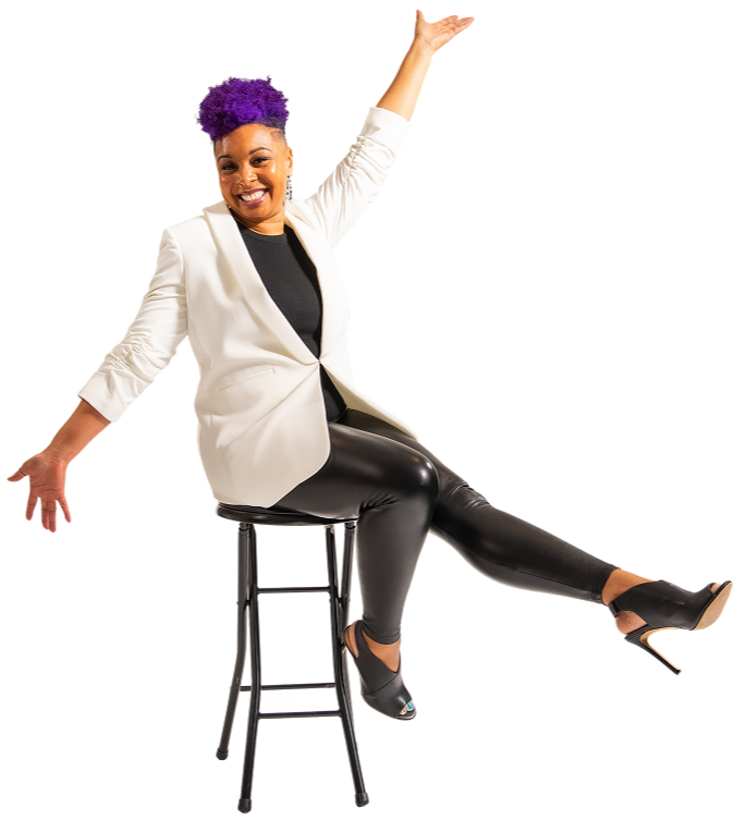 A cheerful woman with purple hair and dark skin sitting on a tall black stool, wearing a white blazer, black top, black leather pants, and open-toe high heels, smiling and raising one arm in a lively pose.