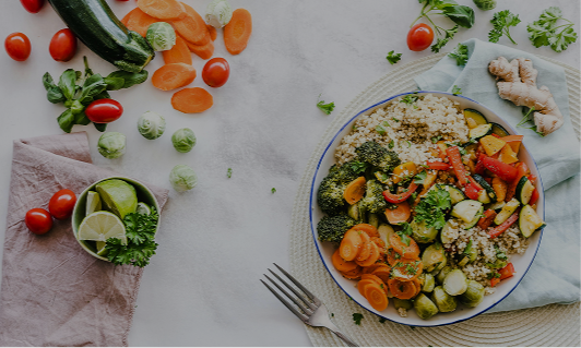 A plate of mixed vegetables and quinoa, with fresh tomatoes, cucumber, and sliced carrots on a white surface.