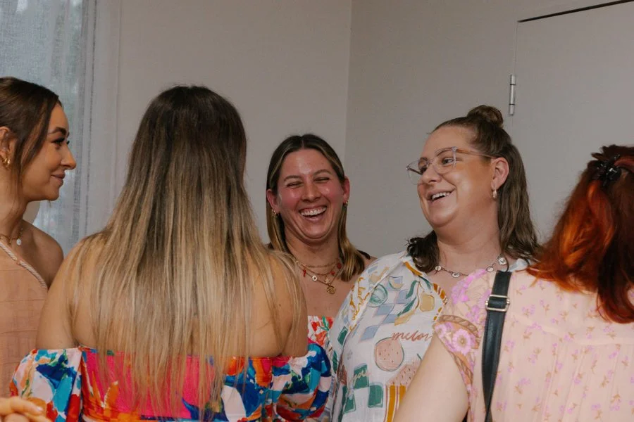 Group of women smiling and chatting at a social gathering indoors.