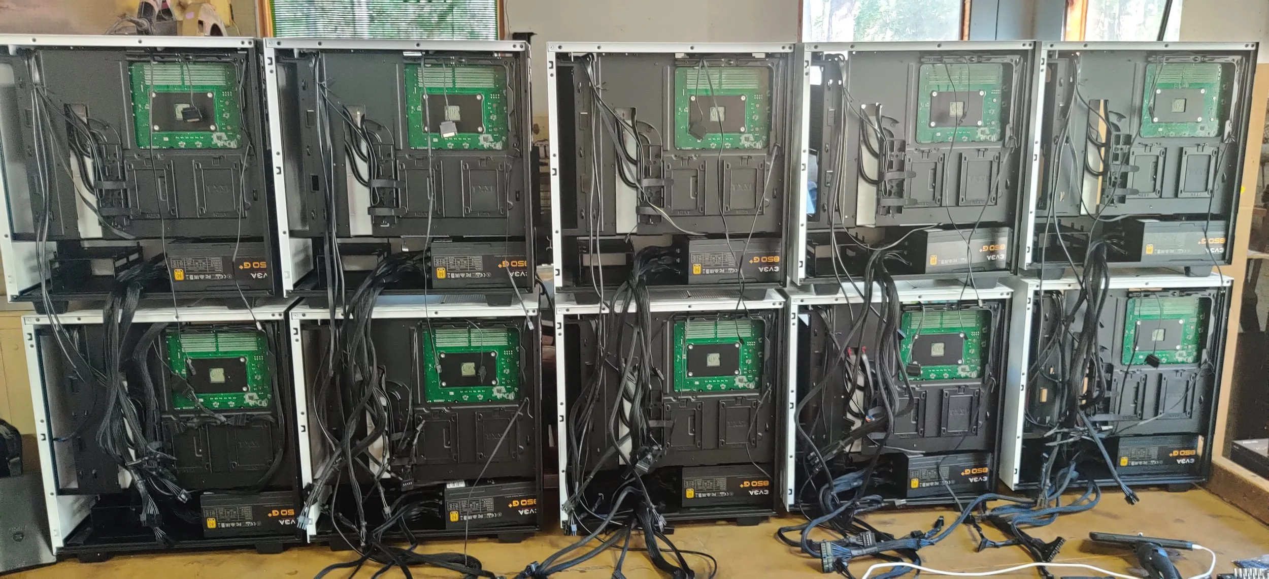 Multiple computer cases with internal components and wiring, arranged on a wooden workbench in a workshop or repair shop.