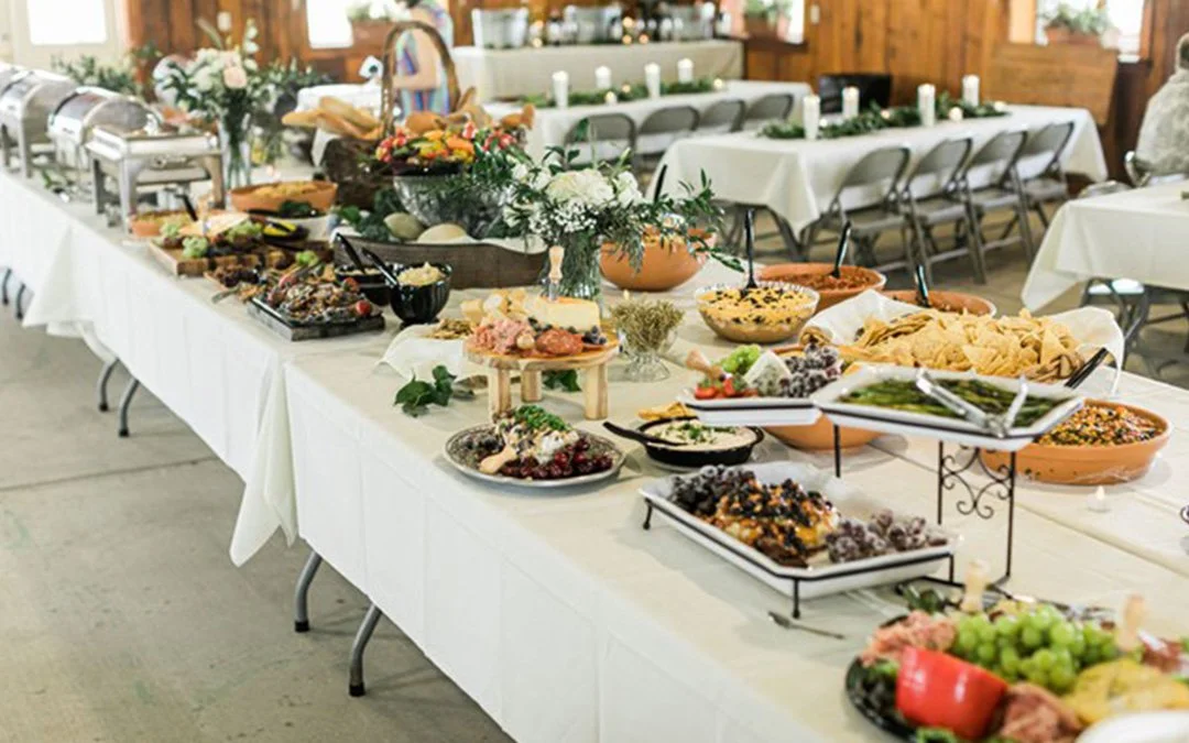 Catering in kingston Jamaica Buffet table with various dishes, salads, chips, dips, fruit, and desserts in a decorated indoor space.
