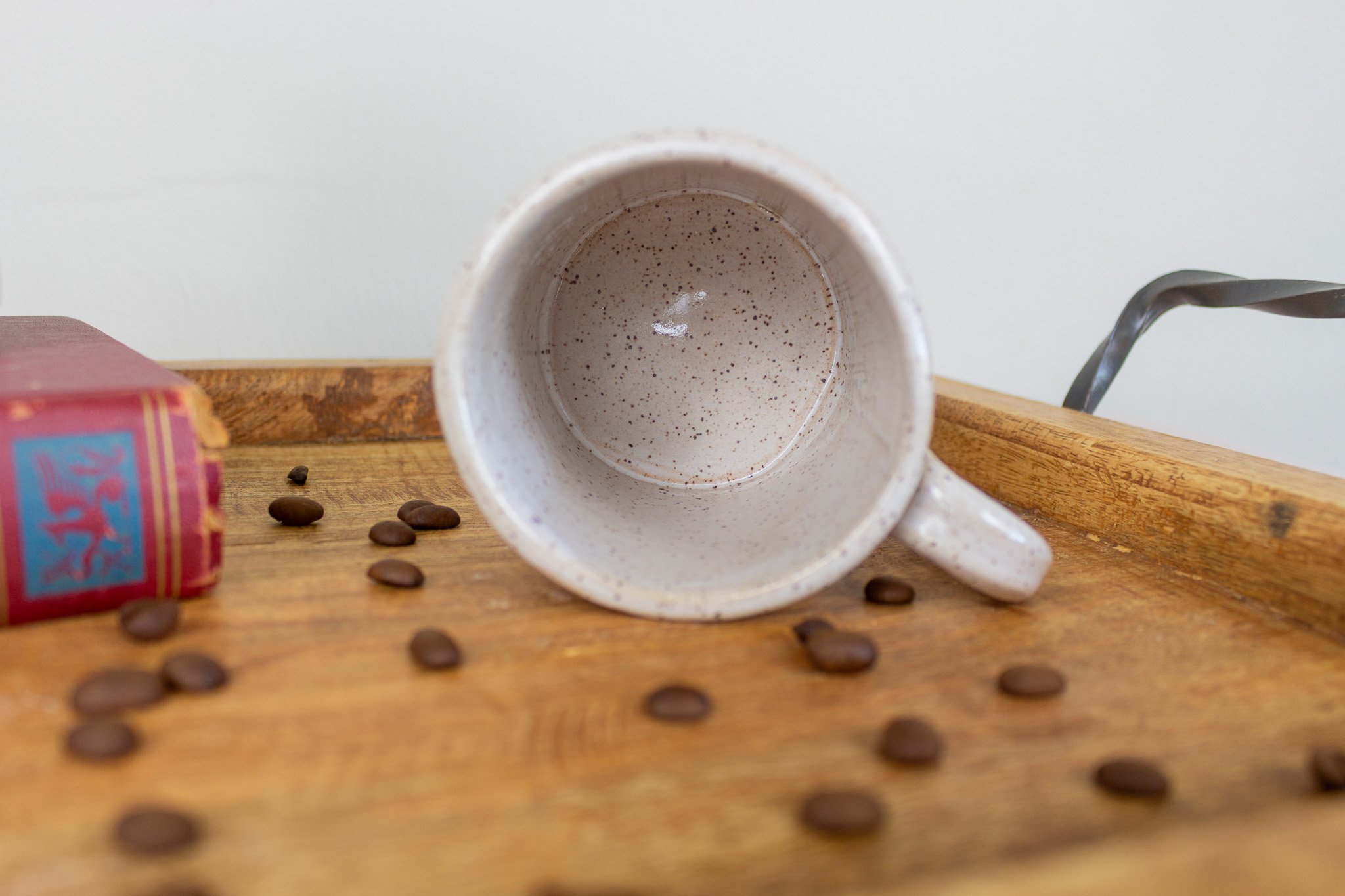 empty handmade mug on it's side showing cream and speckled design.