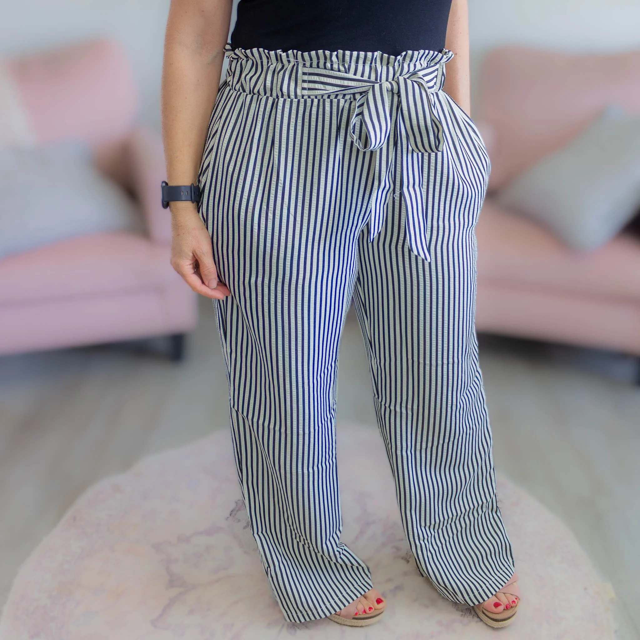 woman turned slightly to side wearing black and white stripe pants with tie waist.