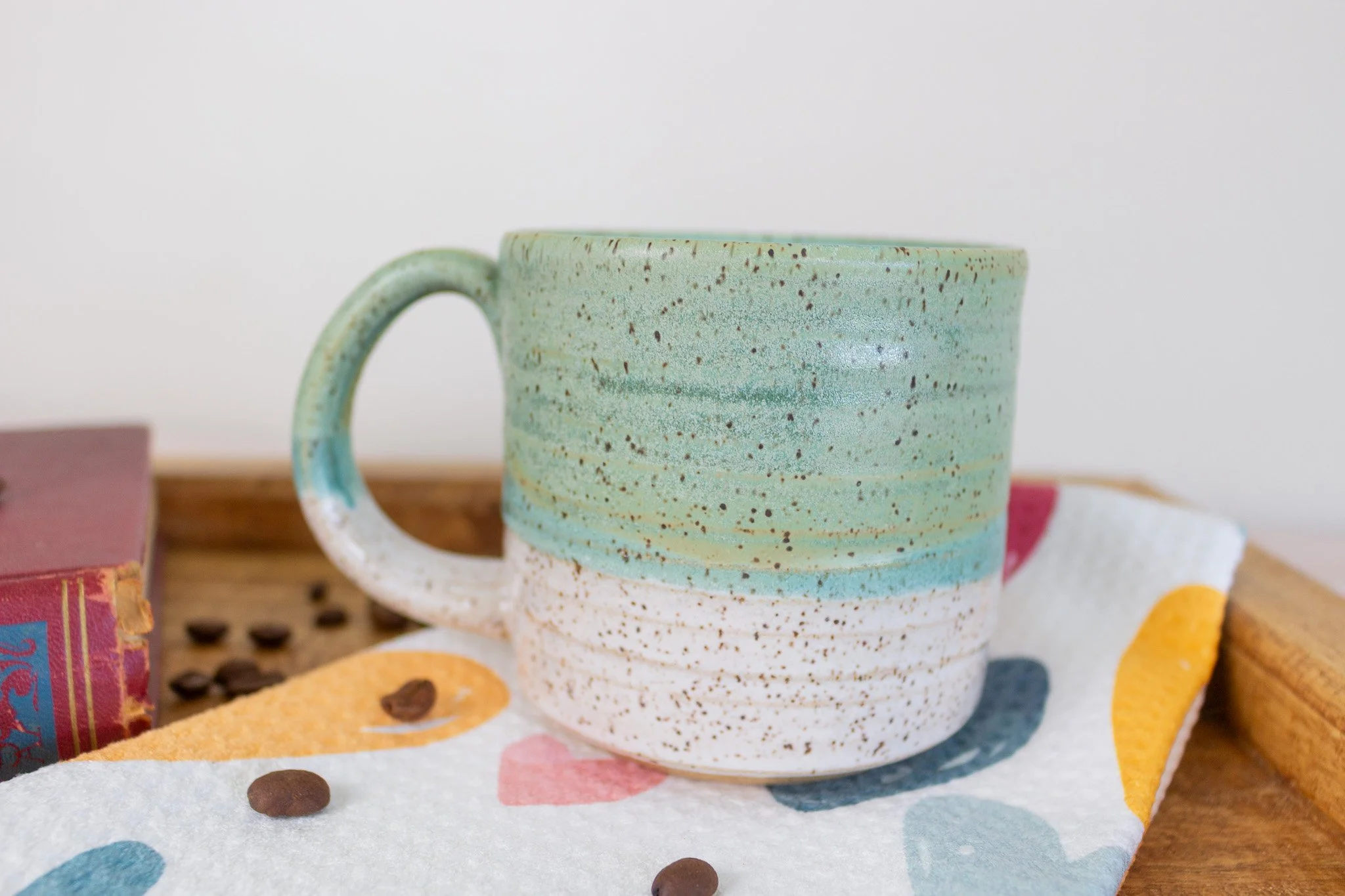 turquoise and cream speckled mug sitting on heart towel.