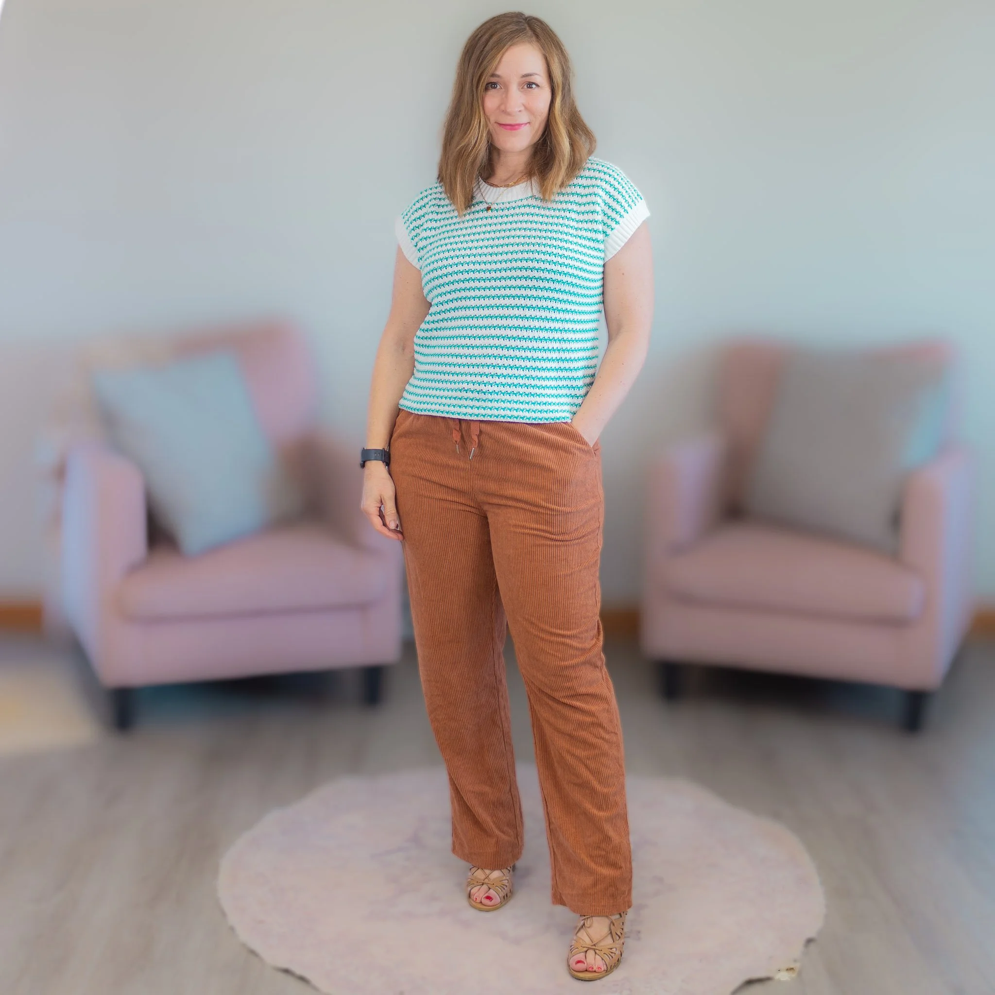 woman standing wearing green and white striped short sleeve sweater and brown pants