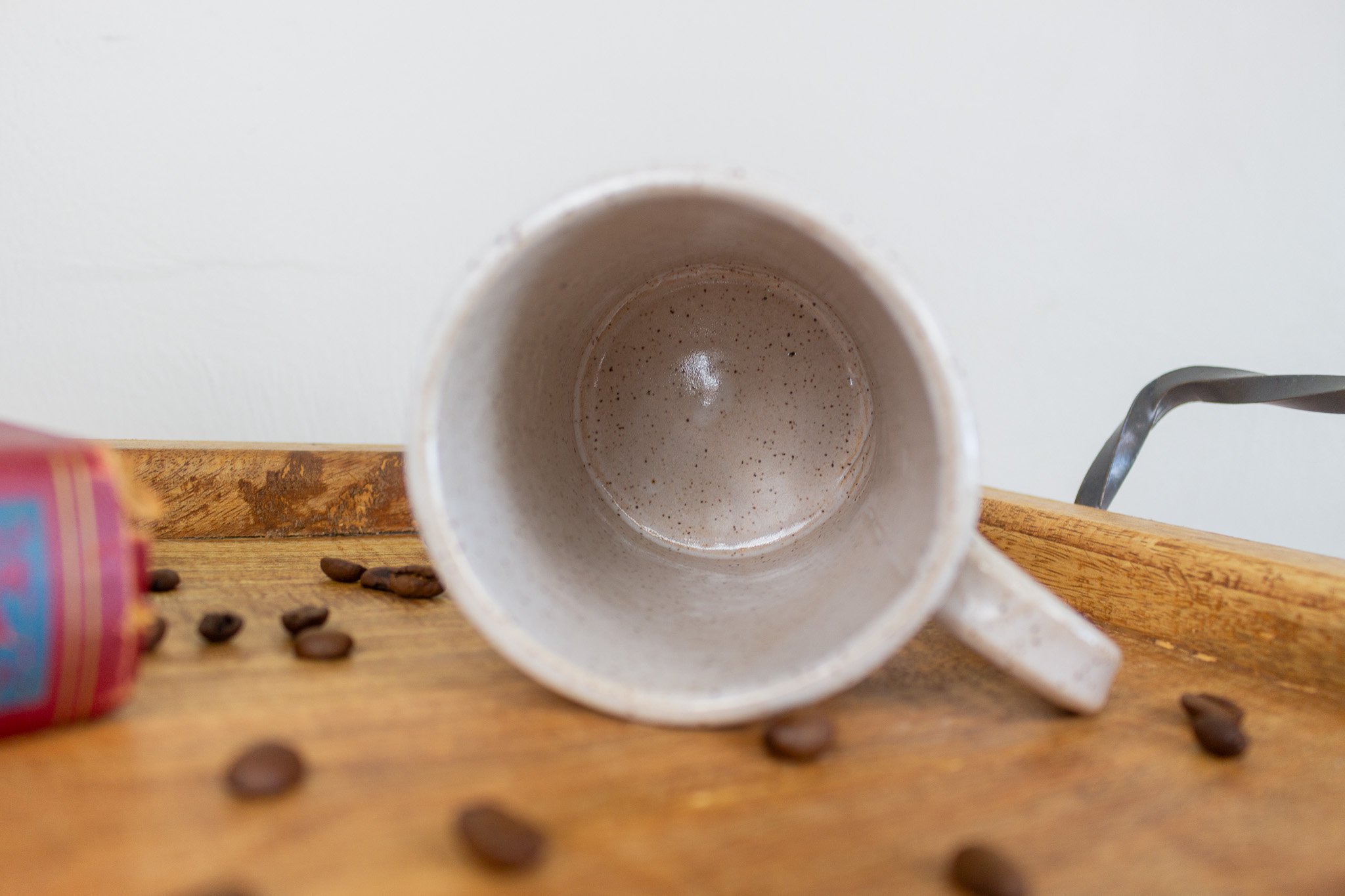 empty mug laying on it's side showing cream and speckled interior.