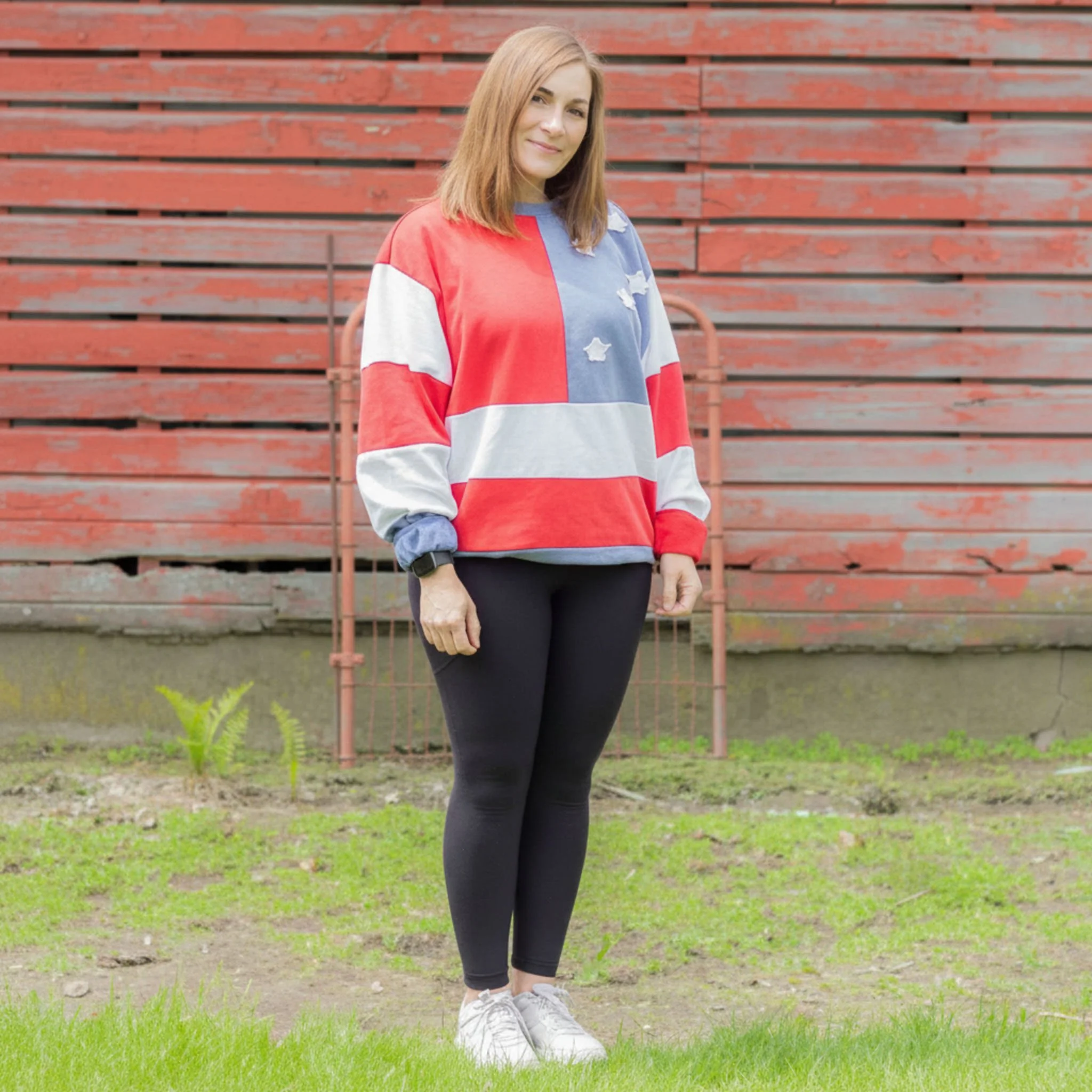 Woman wearing black leggings and sweatshirt with red and white patches, as well as a blue patch with white applique stars.