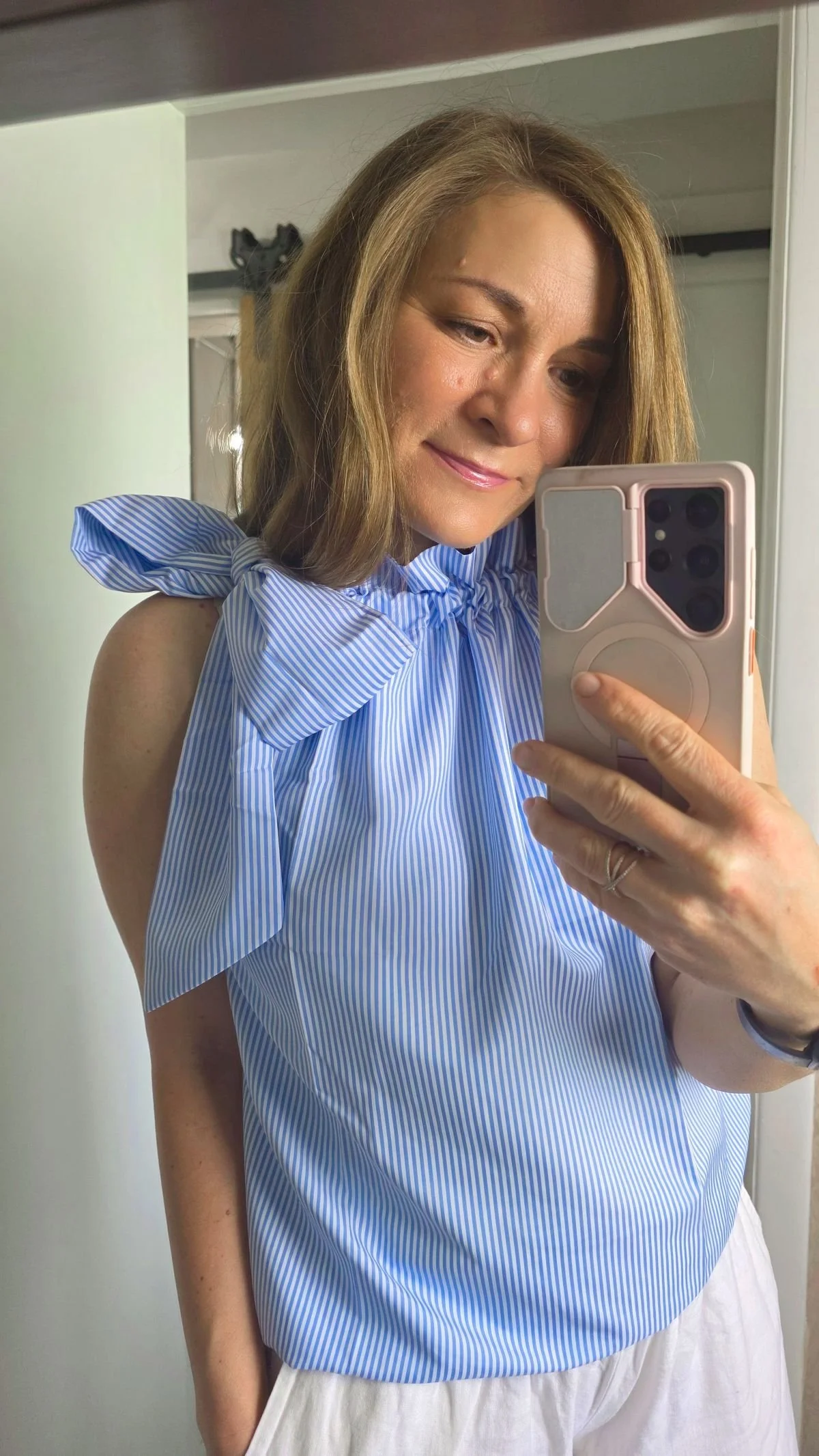 mirror selfie of sleeveless blue and white striped top tied with bow at top of shoulder.