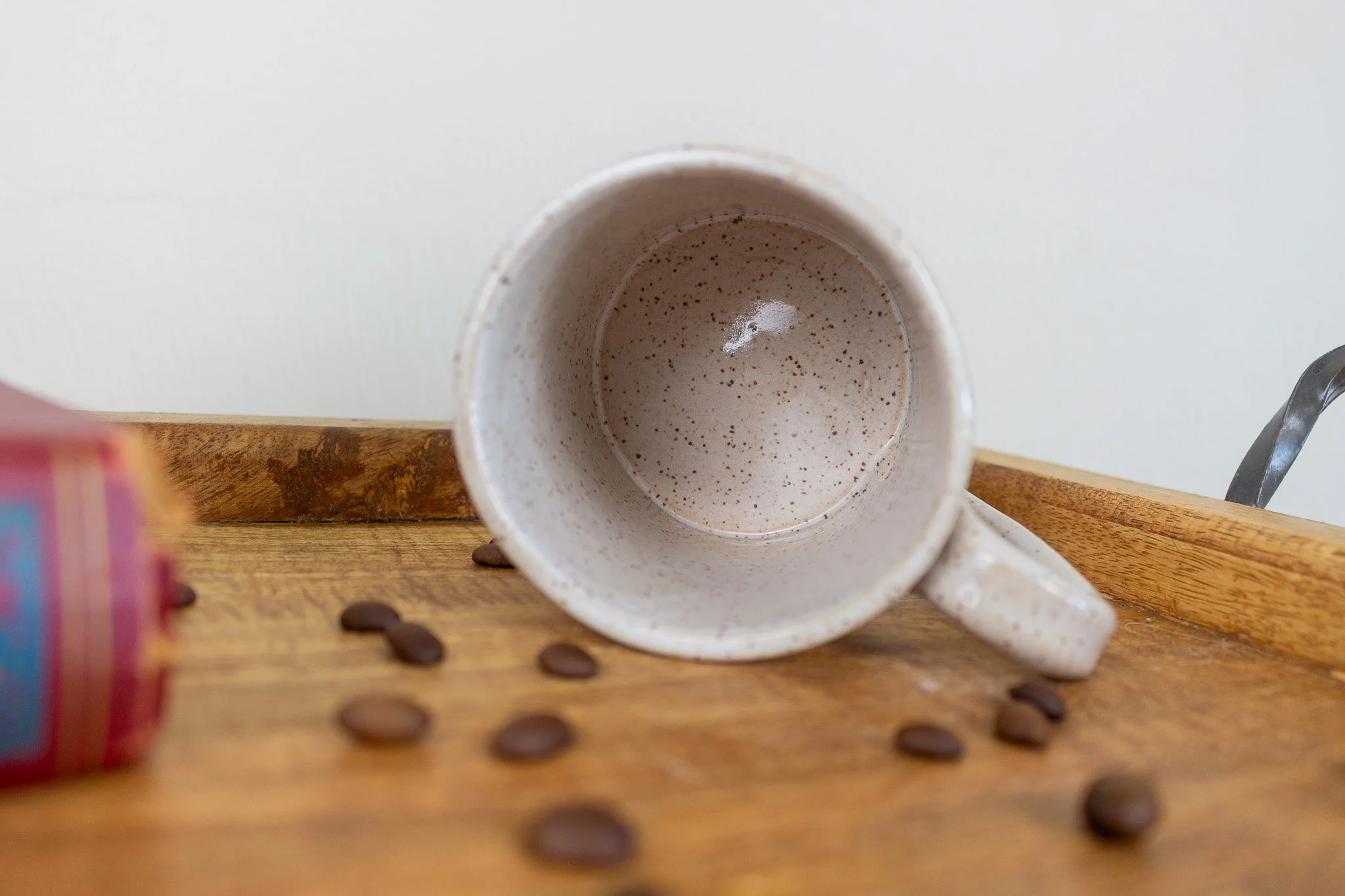 empty black cat mug laying on its side showing it's cream and speckled interior.