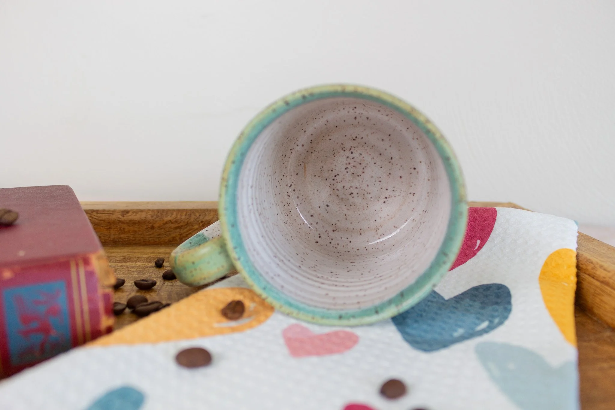 turquoise and cream mug laying on its side showing cream and speckled interior.