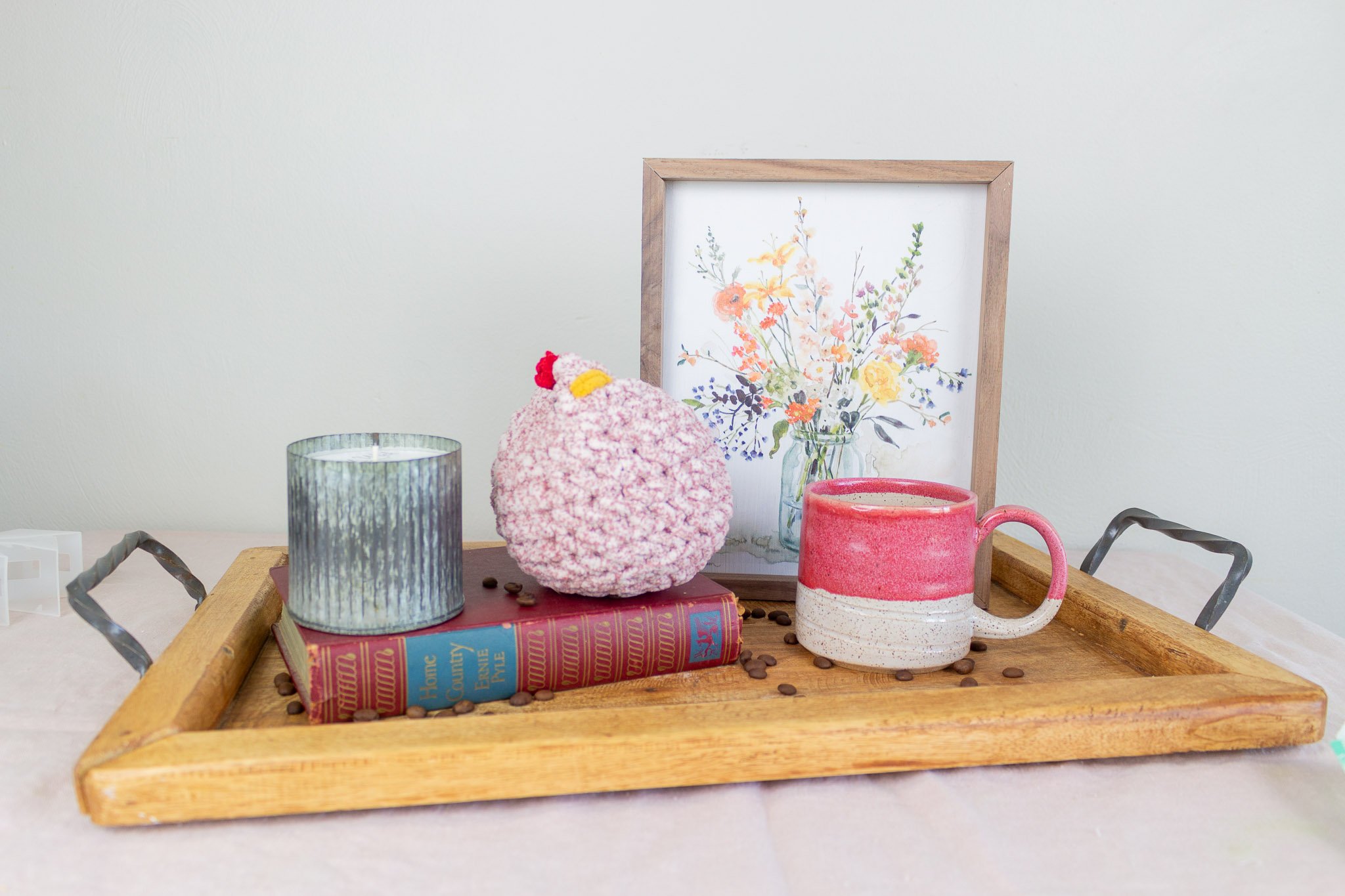 red and cream mug on tray with coffee beans, floral artwork, speckled chicken and tin candle.