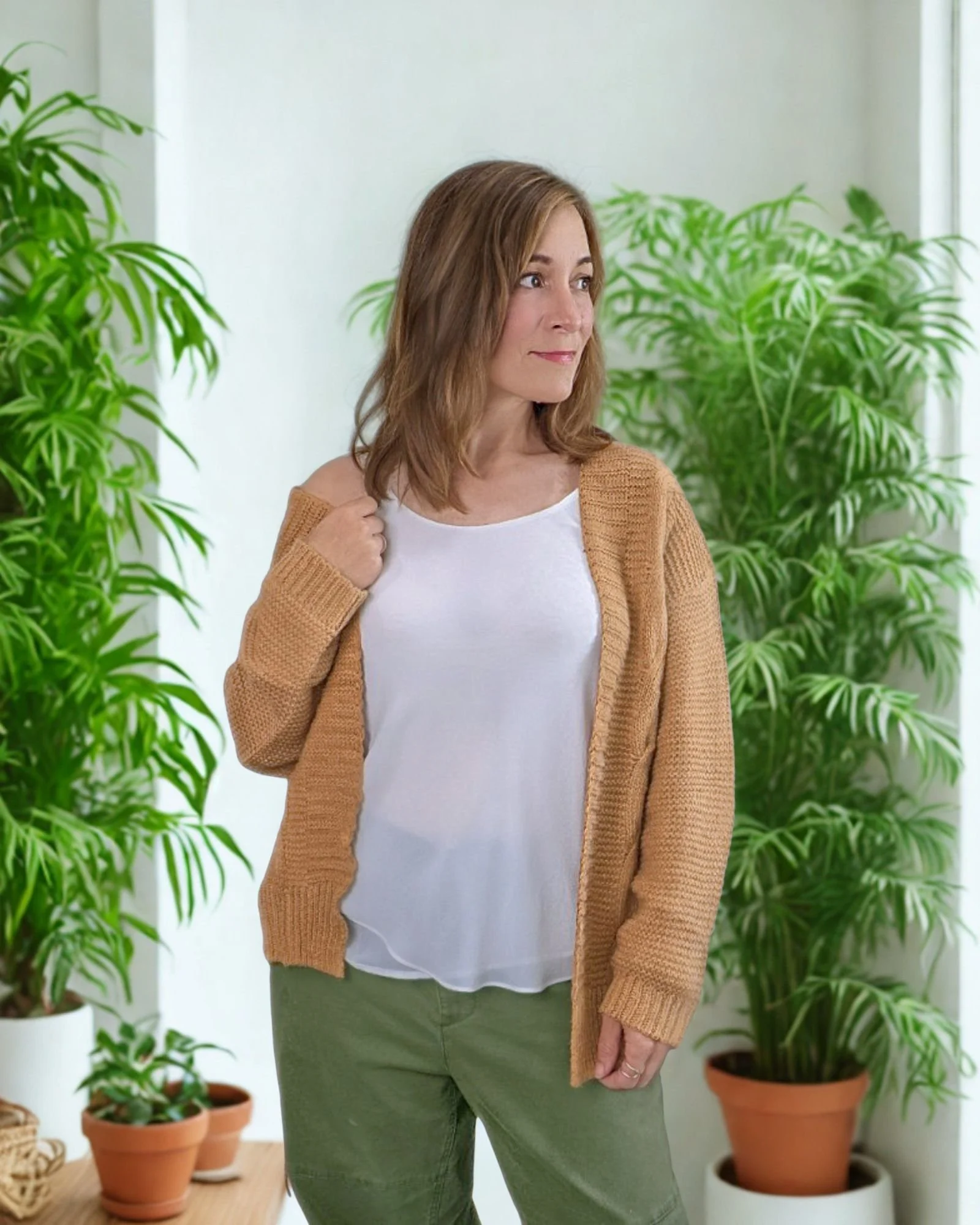 woman wearing loose cardigan in room with plants