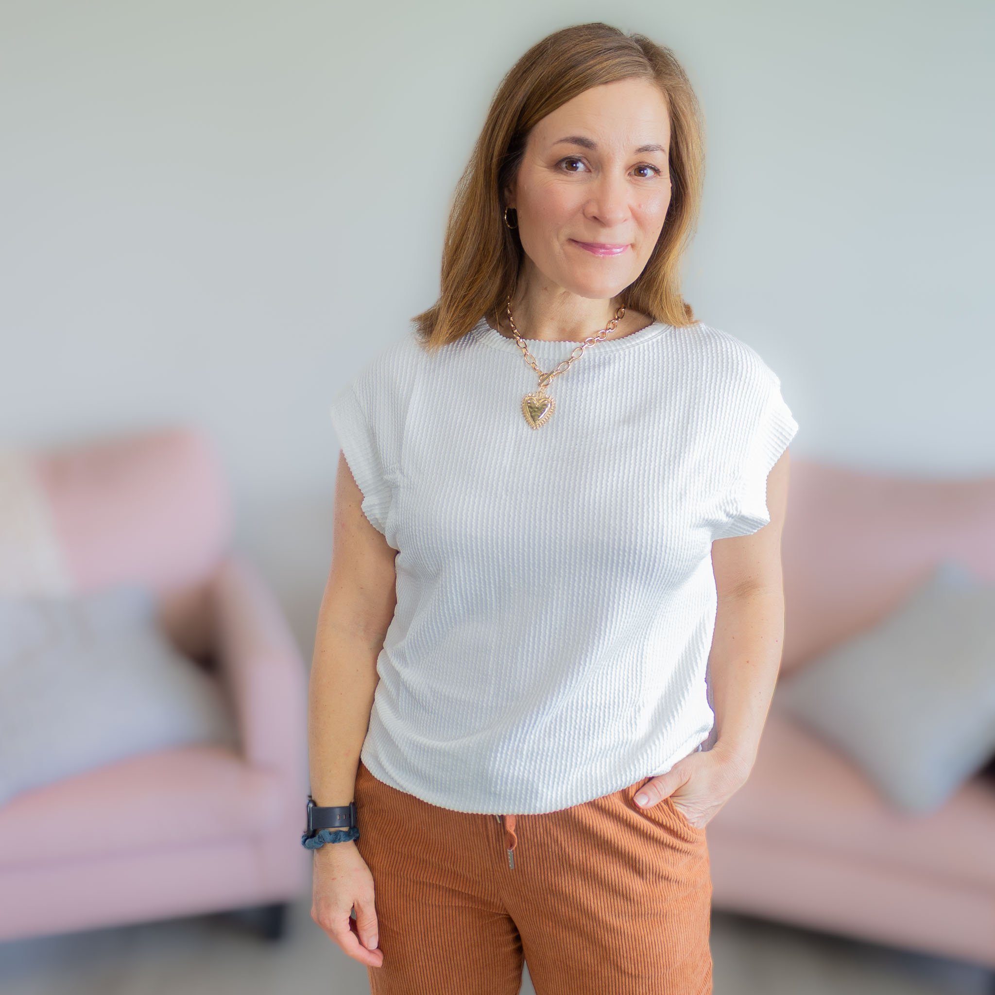 woman wearing white textured top with gold necklace.