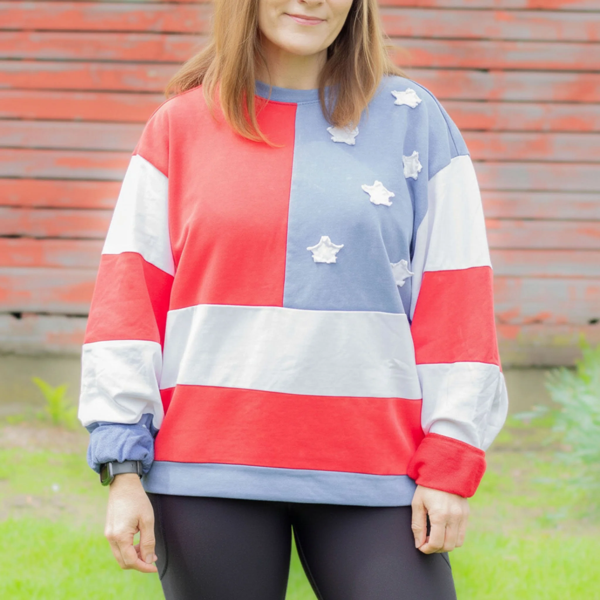 Close up of sweatshirt with red and white patches, as well as a blue patch with white applique stars.