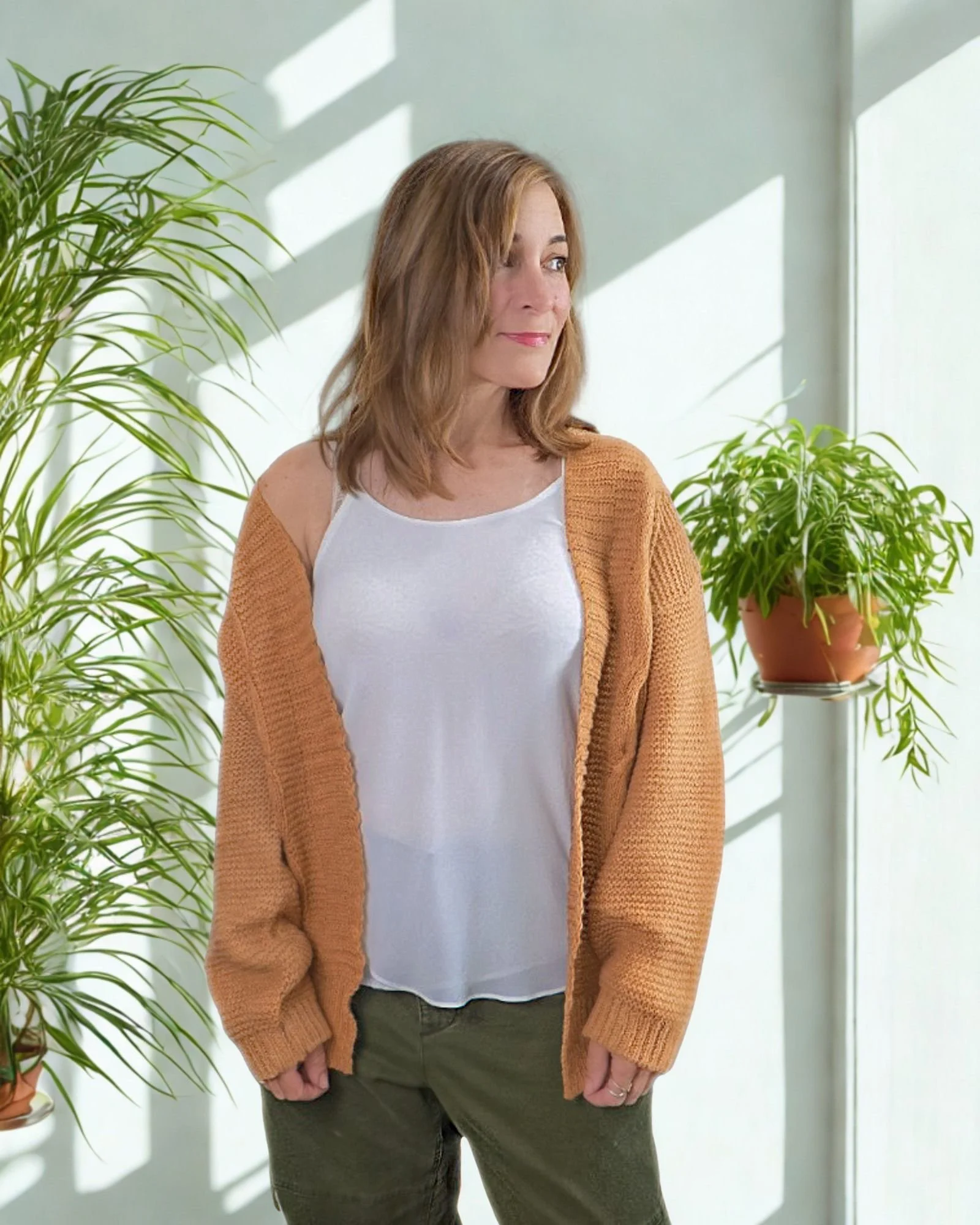 woman looking to side wearing khaki cardigan and cream cami.