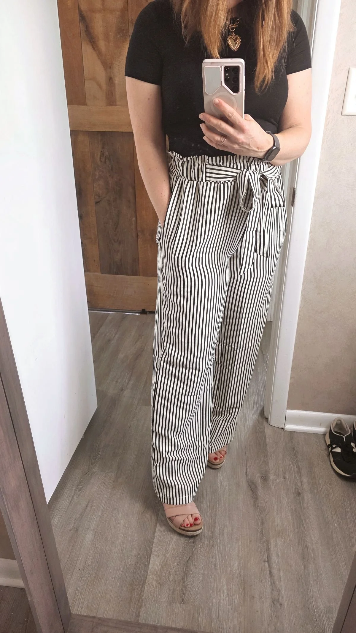 mirror selfie of black and white striped pants with a bow tied at waist.