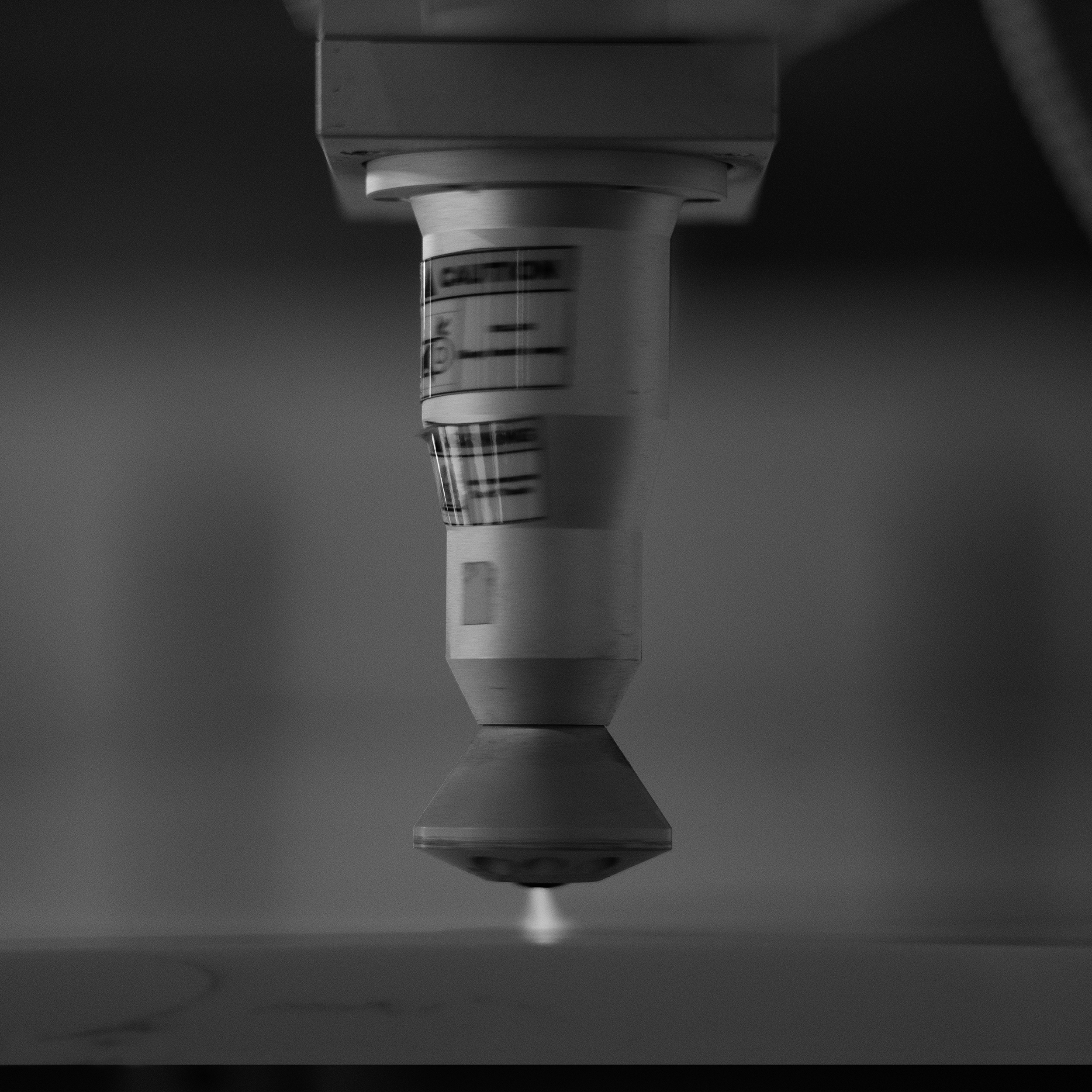 Close-up of a syringe needle hovering above a surface, with a blurred background.