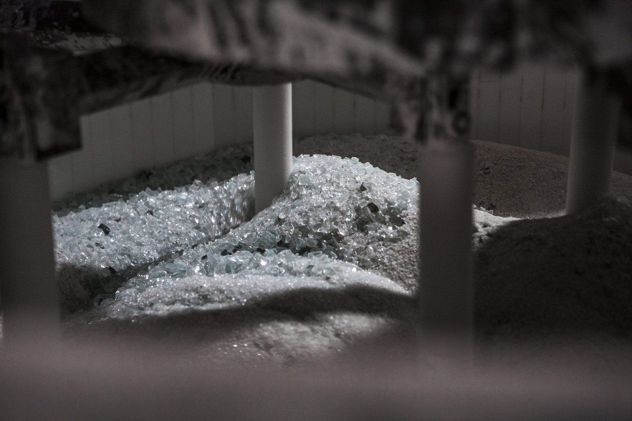 Glittering shards of broken glass spilling from a container with a dark background.