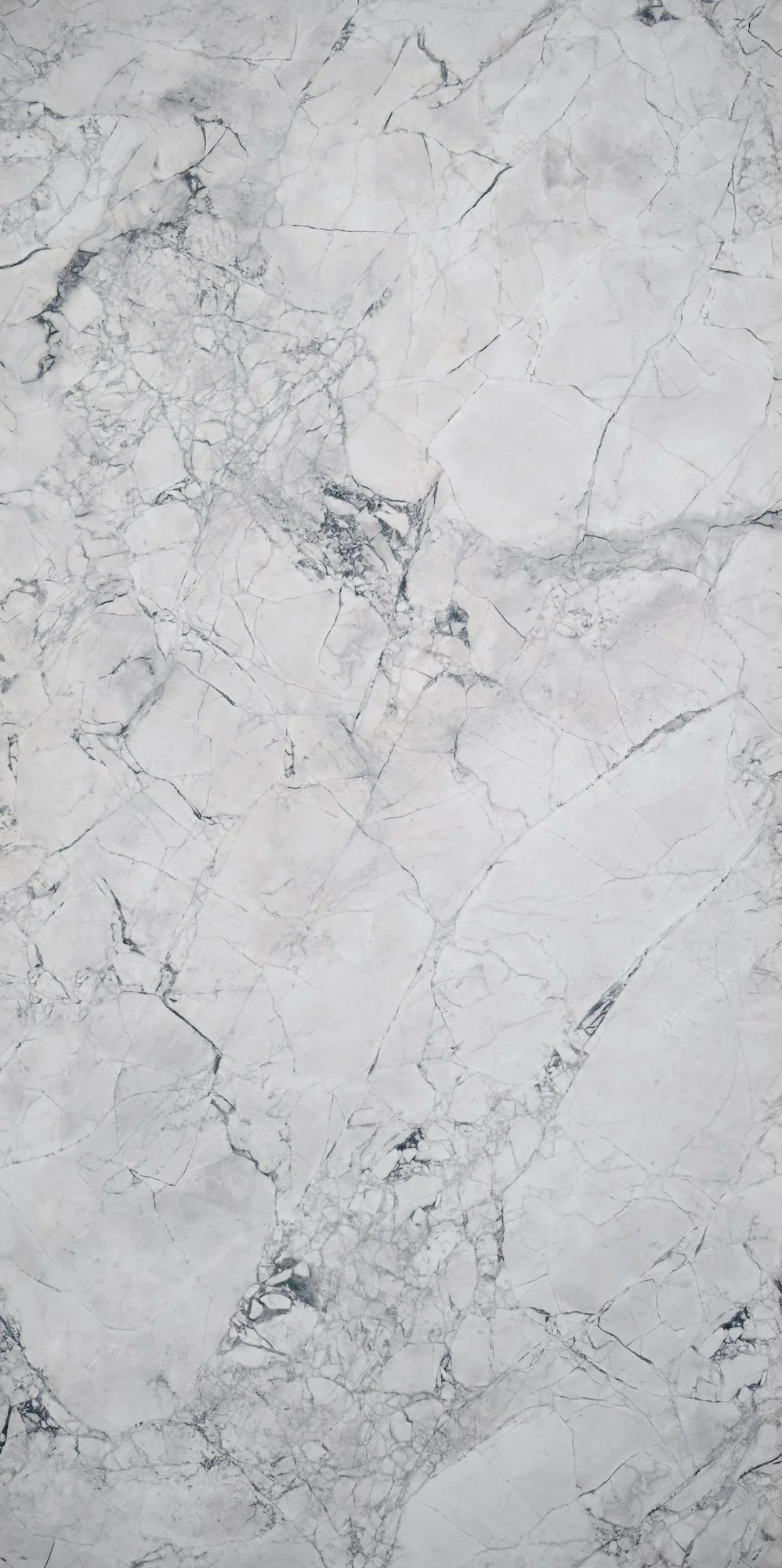 Close-up of a white marble surface with gray veining and cracks.