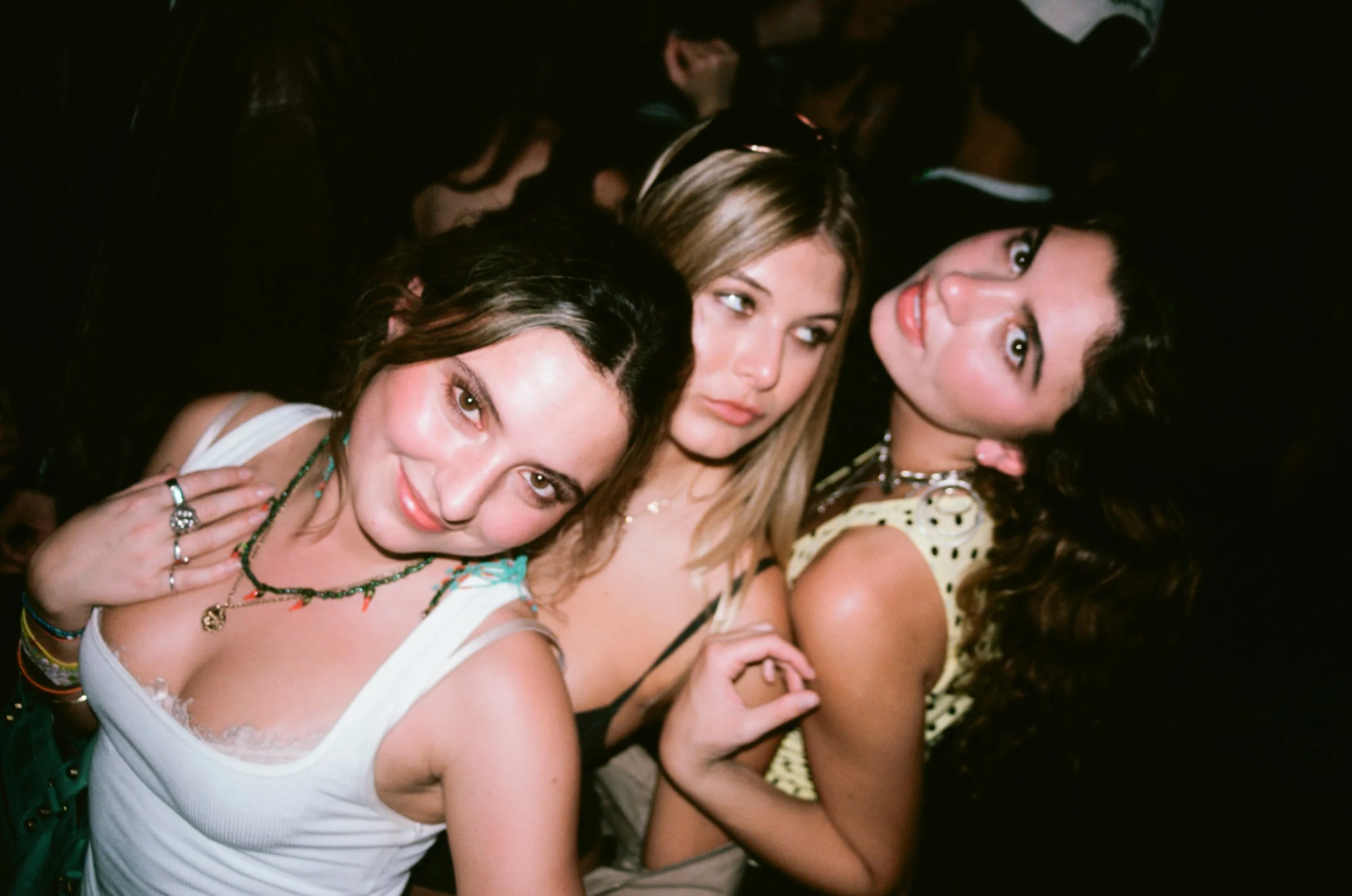 Group of young women at a party, posing closely together with expressions of fun and confidence.