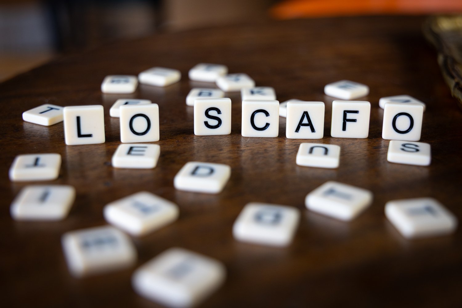Scrabble tiles spelling 'LOS CAFO' on a wooden table.