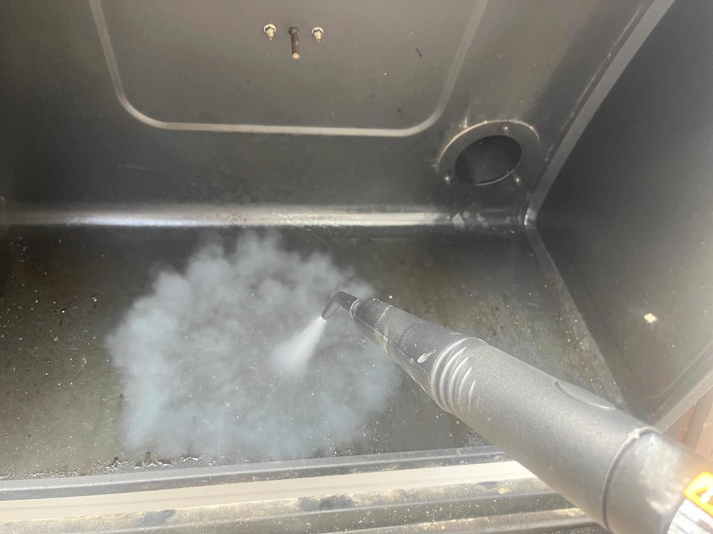 Professional grill repair technician steam cleaning and diagnosing a BBQ grill issue