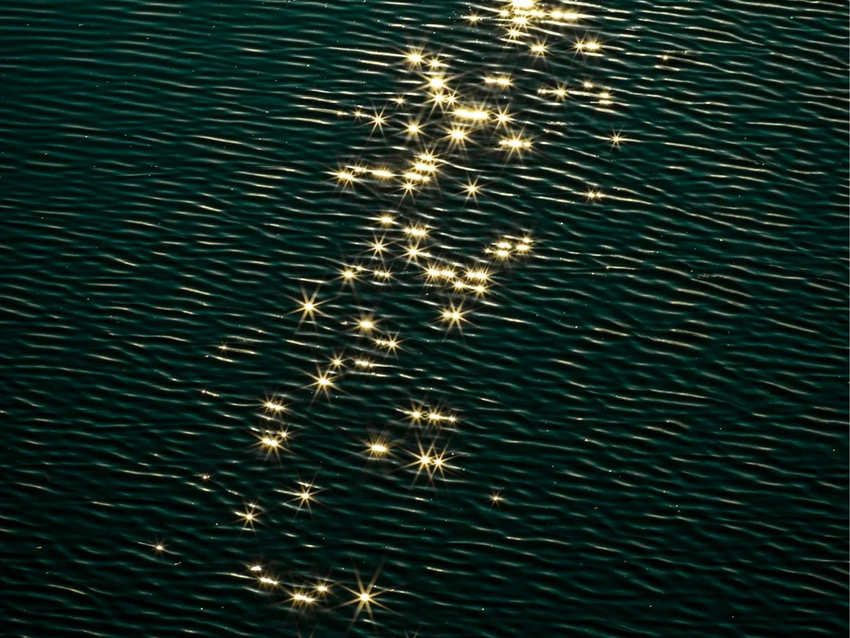 Sunlight reflecting off rippling water with a trail of bright stars.