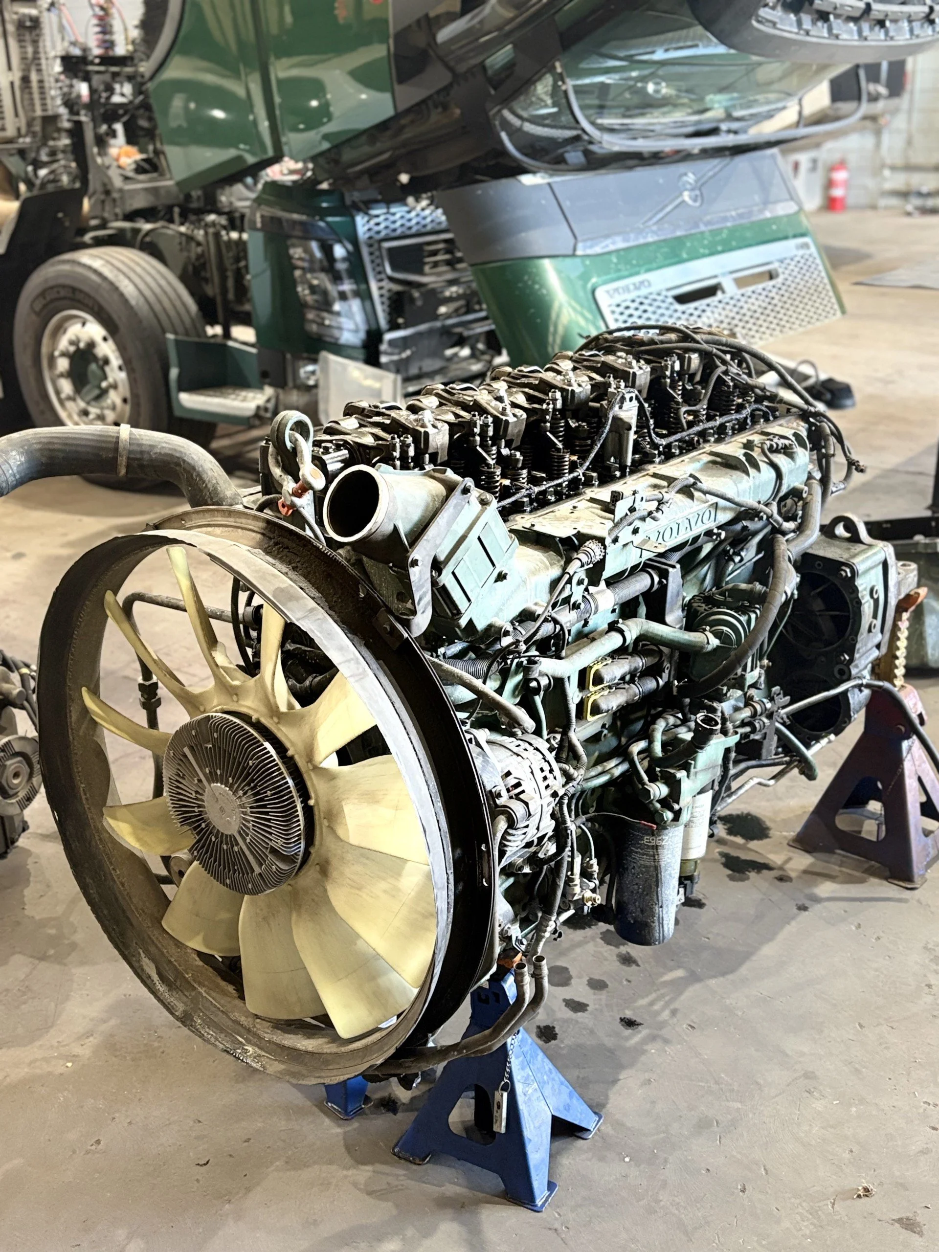 A disassembled airplane engine with a propeller, placed on a stand in a workshop or garage.