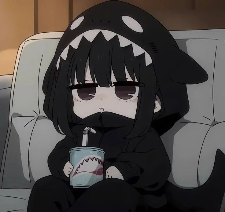 A cute cartoon character with black hair, wearing a shark hoodie, sitting on a couch and drinking from a cup with a shark face on it.
