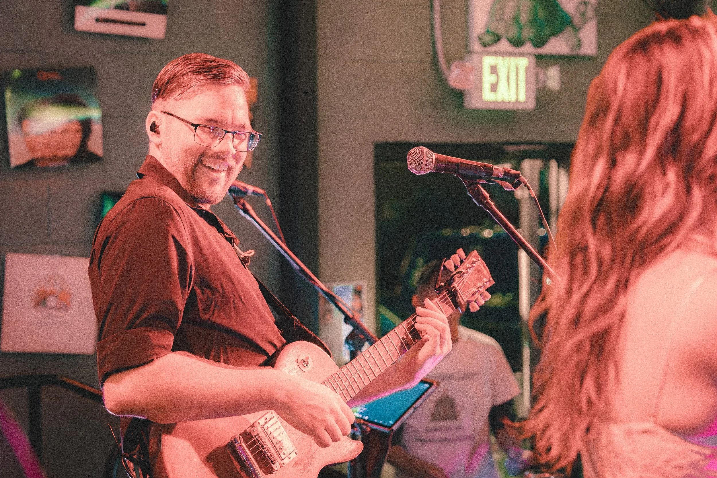 Mason James smiling while playing rhythm guitar onstage.