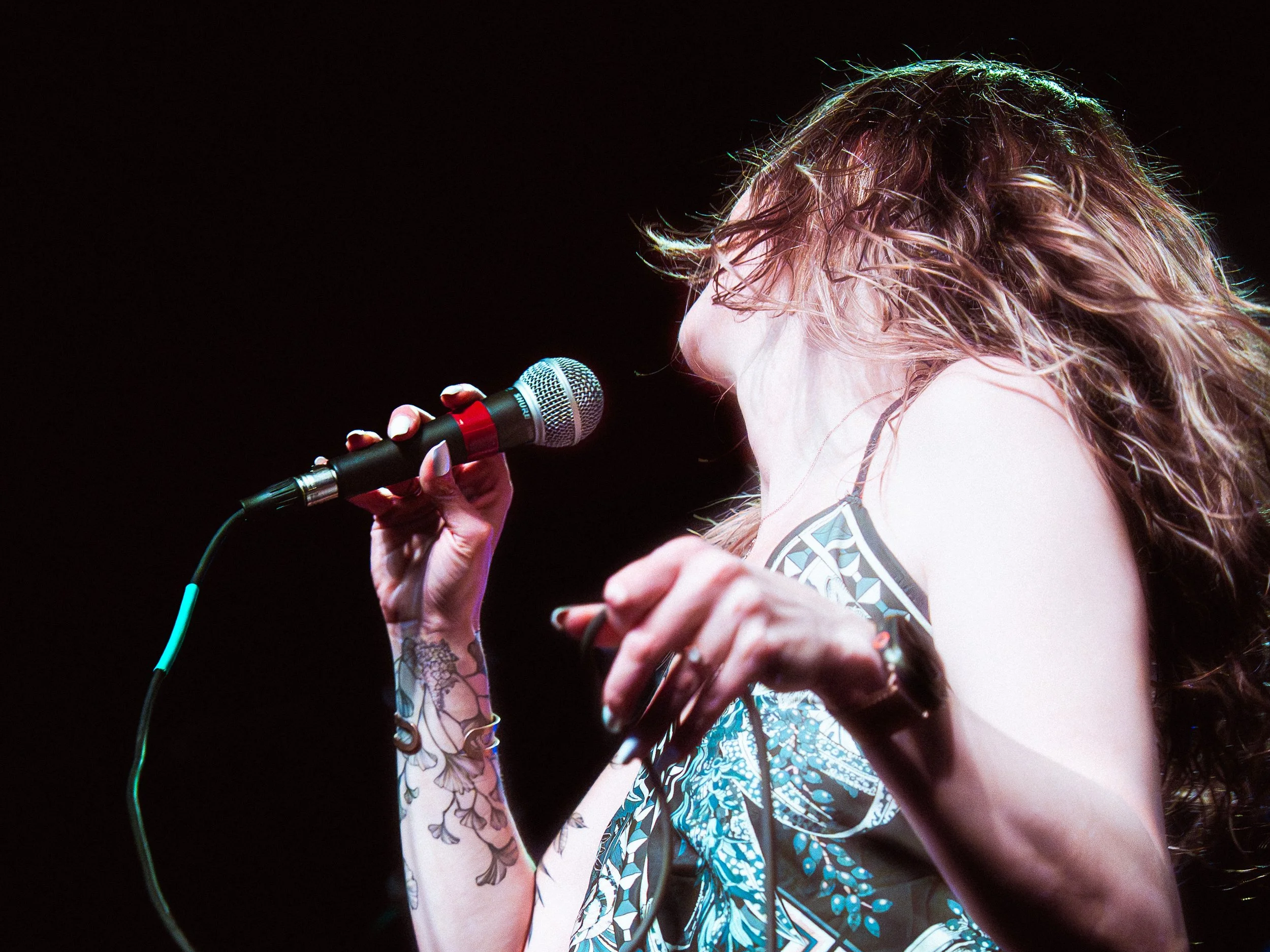 Close-up of Liz Bauer holding a microphone during a live show.