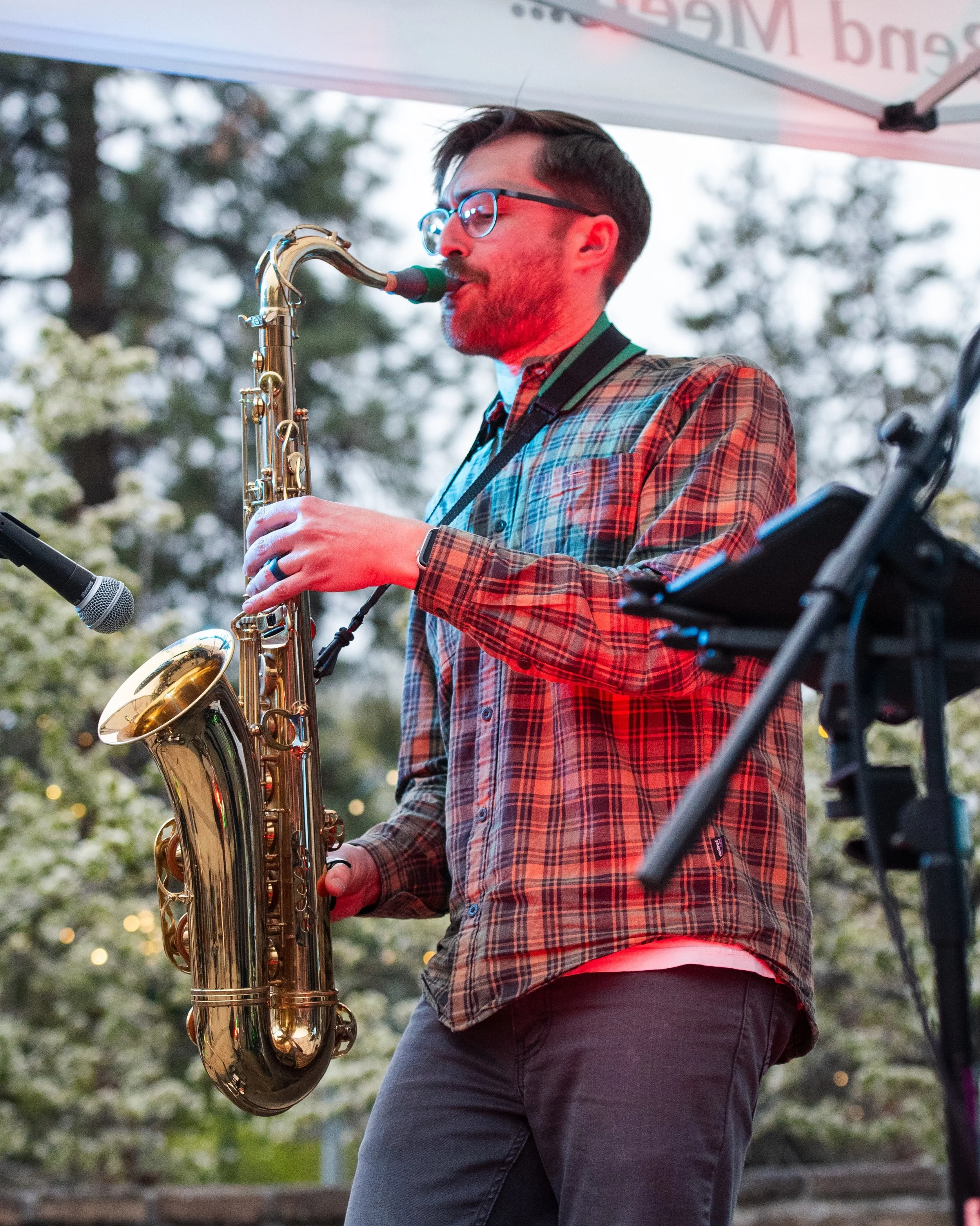 Zach Harju, saxophonist and keyboardist for Funk Around & Find Out, playing saxophone at an outdoor concert.