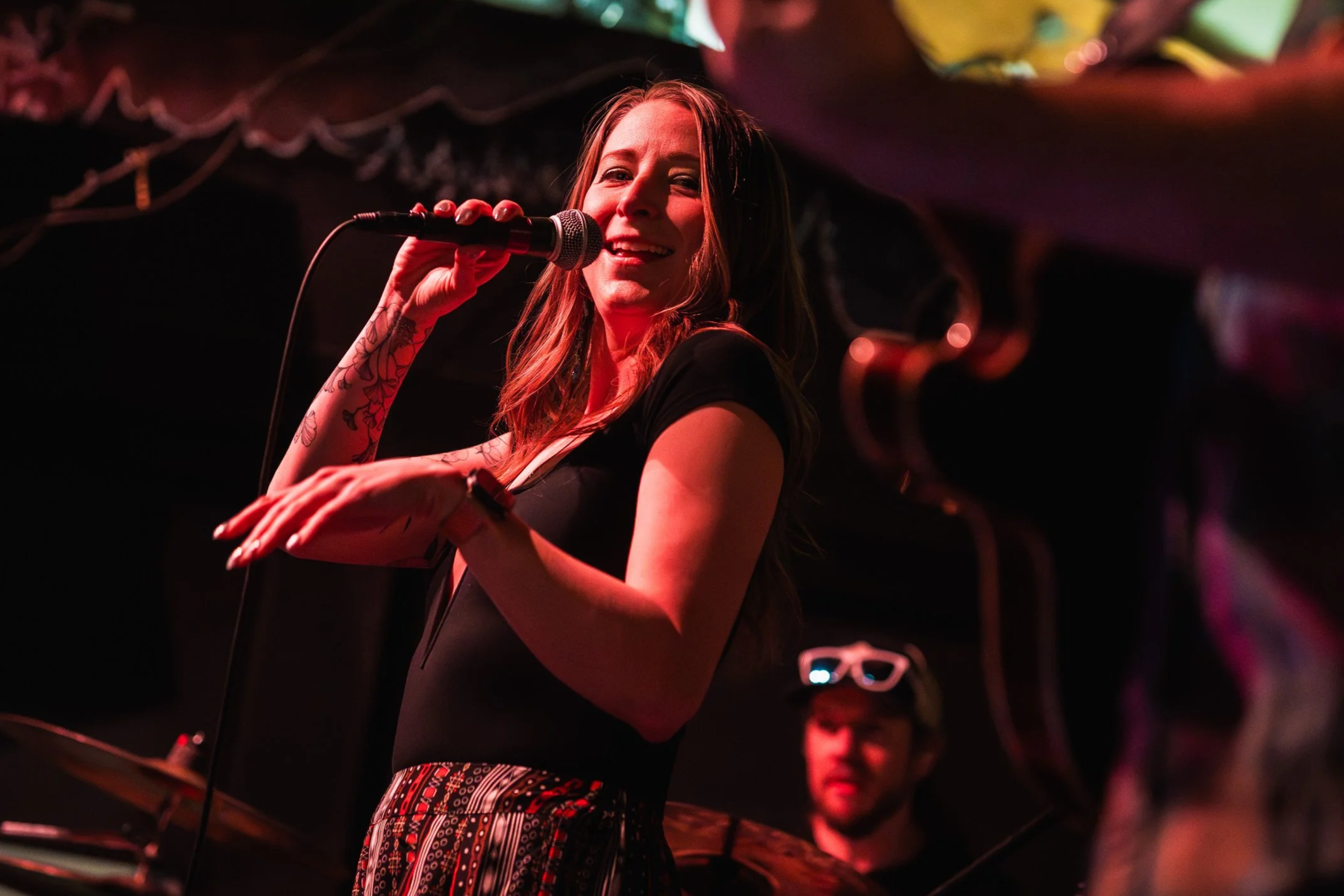 Liz Bauer, lead vocalist for Funk Around & Find Out, singing onstage during a live performance.