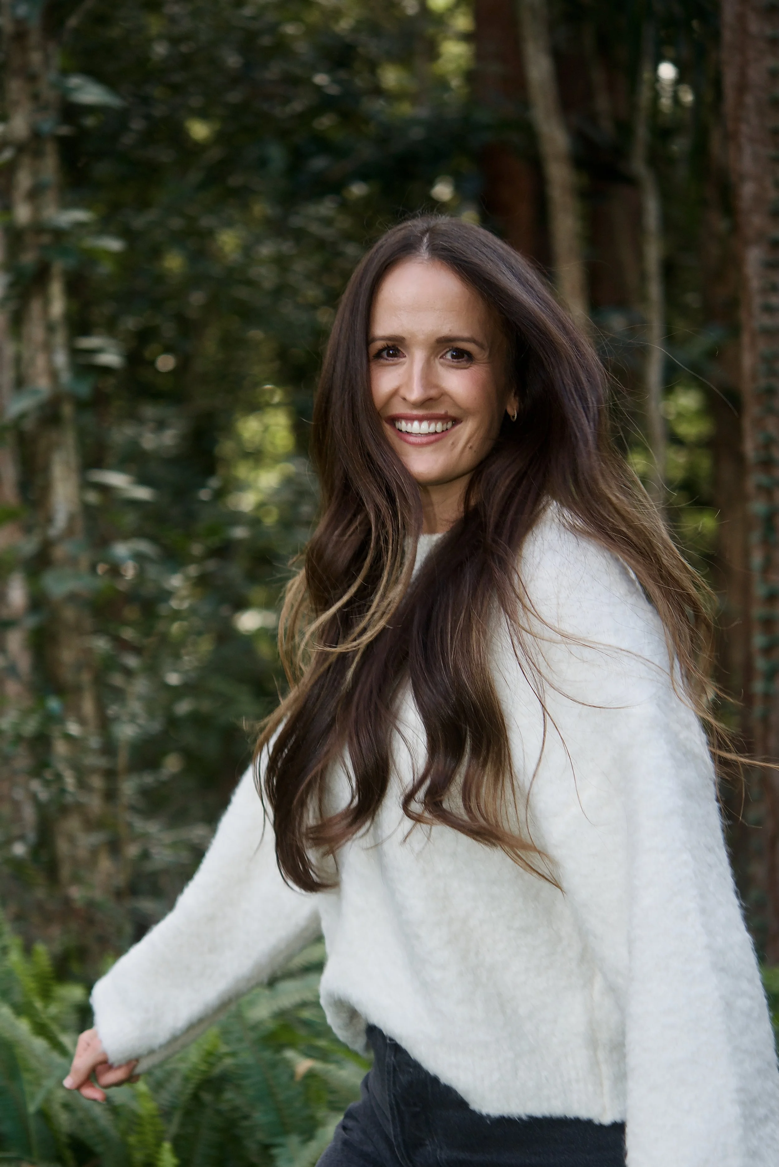 Hayley Hughes, debut author of Thank You, Burnout: From depletion to peace. Hayley walks in nature, turning to look at the camera with a smile. Hayley's long, flowing hair shows her movement. Thank You, Burnout releases April 2026. Hembury Books.