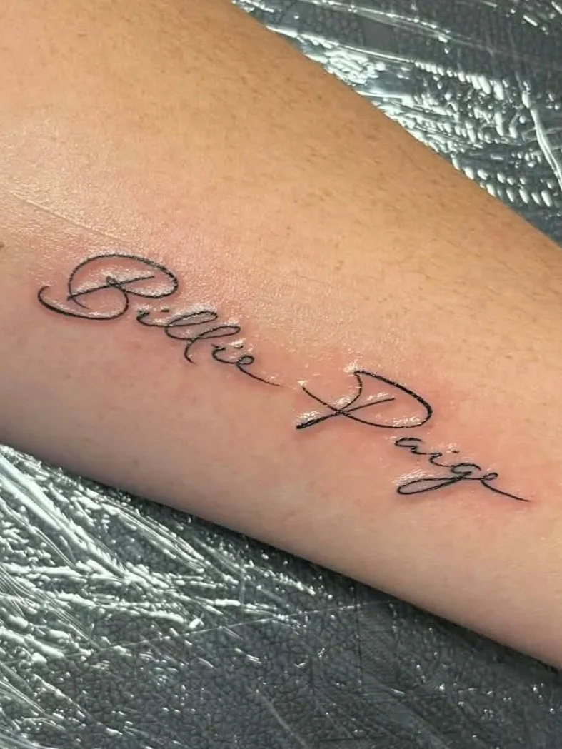Tattoo on skin that says 'Bite My' in cursive font