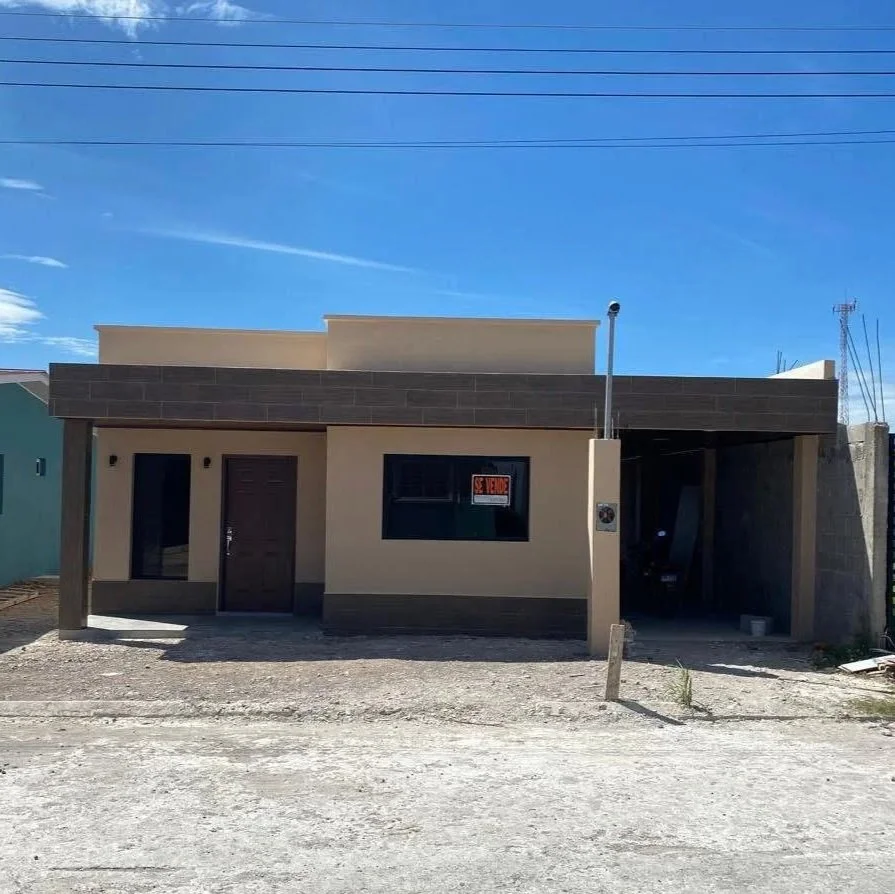Newly constructed house with a 'for sale' sign in the window, front driveway, and clear blue sky.