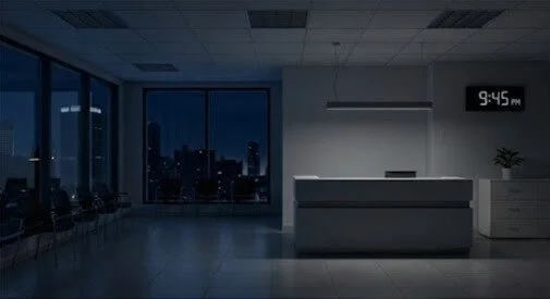 Sala de espera vacía en un hospital o clínica con ventanas de noche y un reloj digital que marca las 9:45 pm.