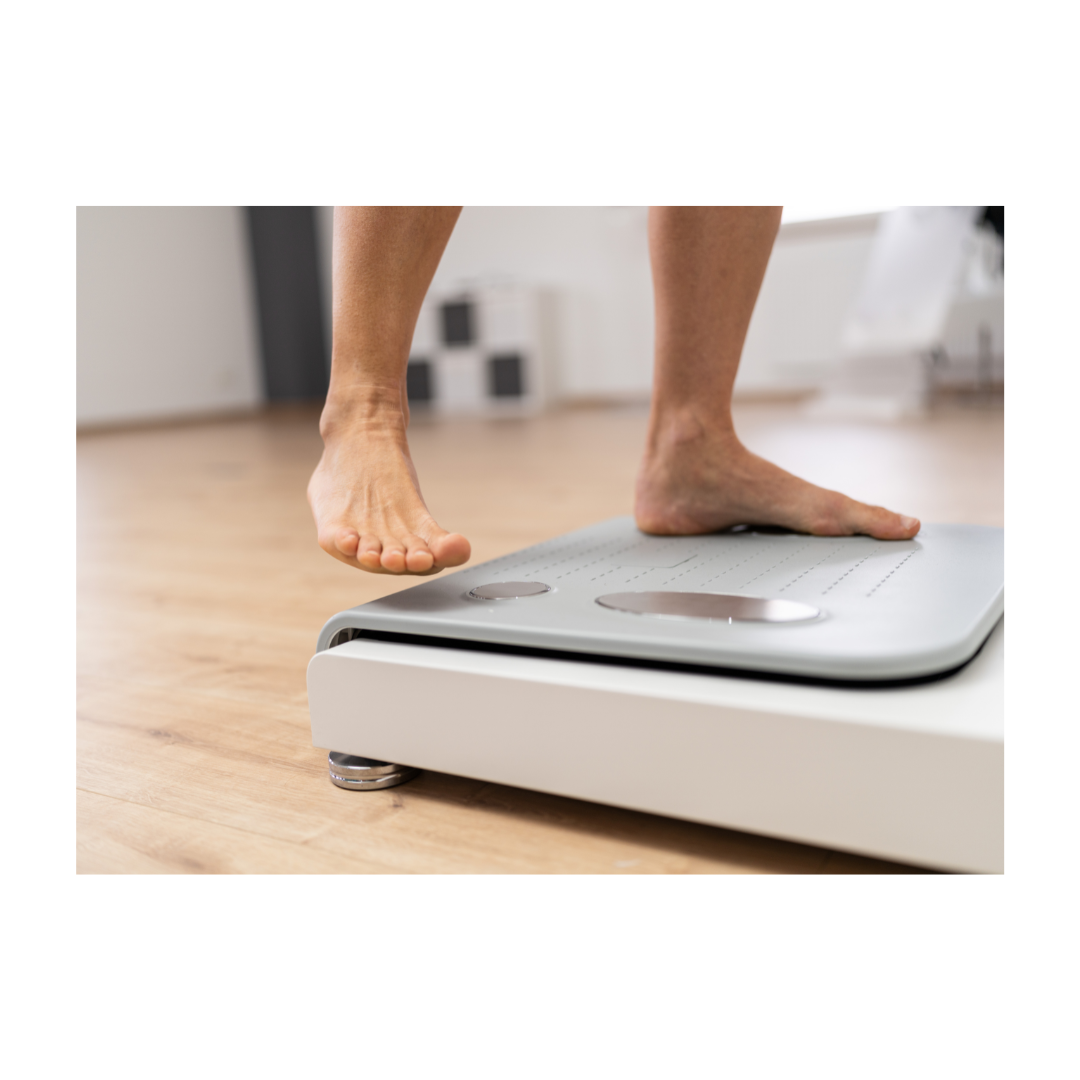 Close-up of a person standing barefoot on a digital bathroom scale indoors with a light wood floor and a white wall.