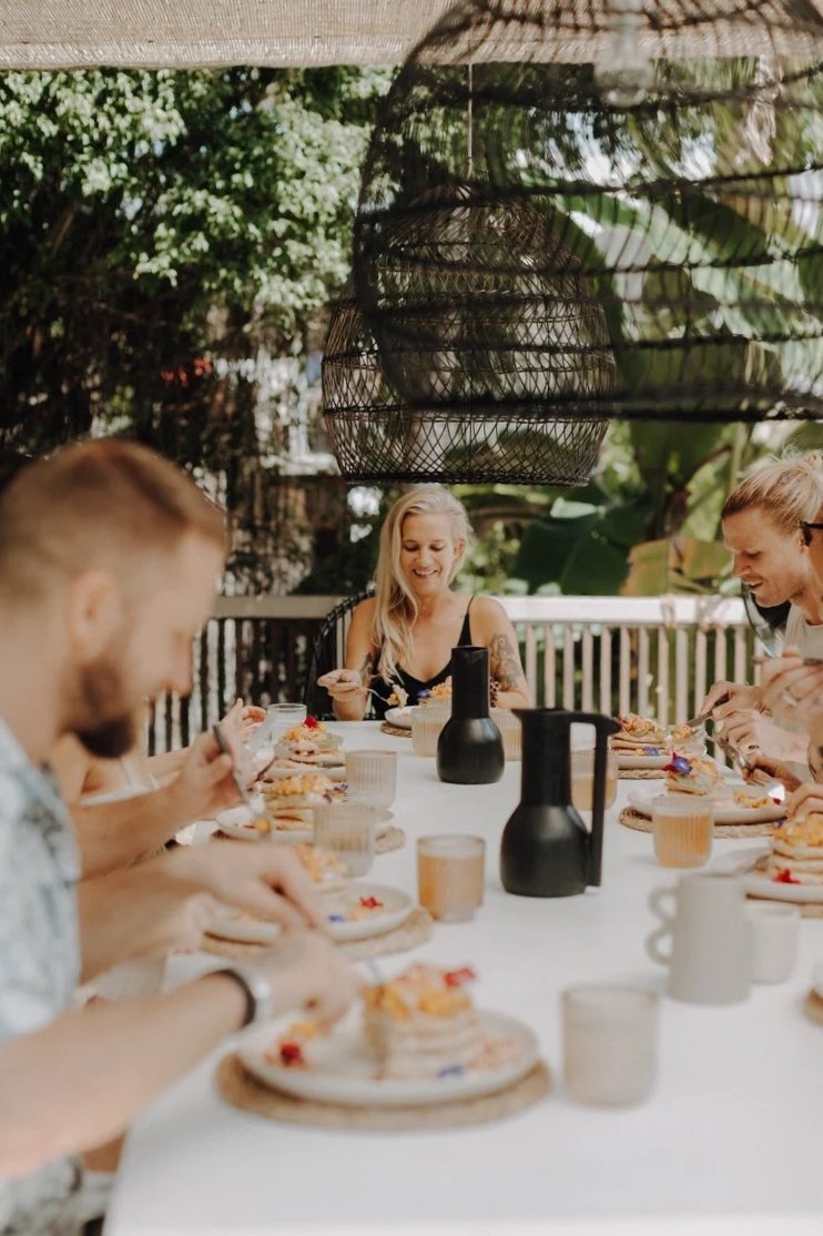 EarthLinks guests enjoying dessert and drinks at an outdoor table in the garden, surrounded by greenery and lanterns.