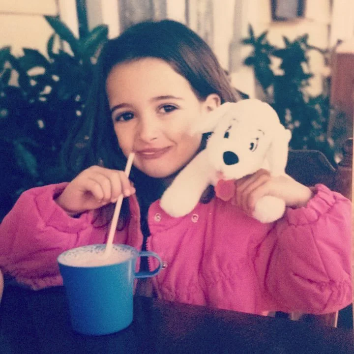 Sam Freidin pictured as a kid in a pink jacket, with a toy dog from 101 Dalmatians, drinking a cup of Nesquick's pink milk. A 90s icon.