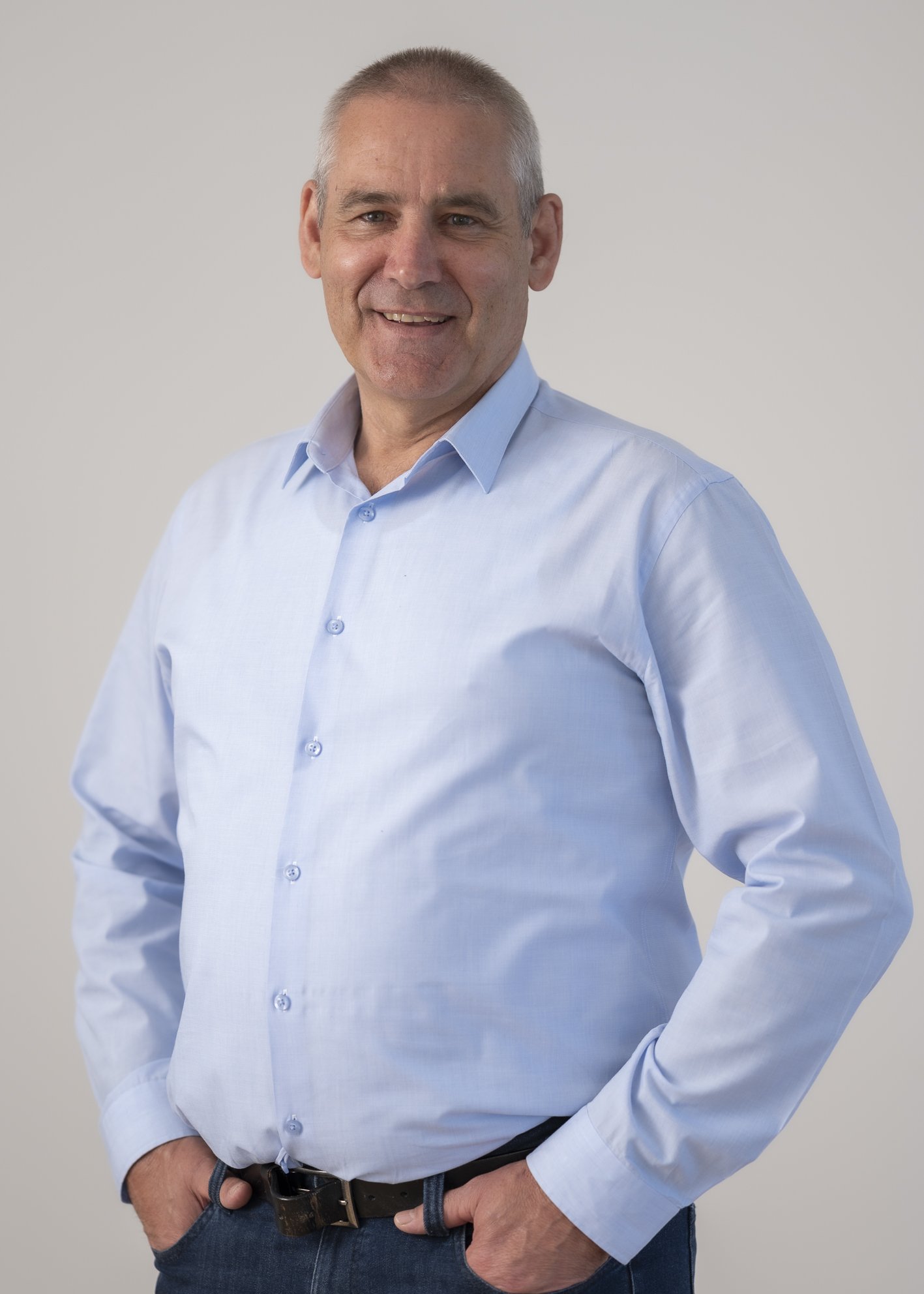 Portrait of Dr Neil Harding, Trustee, standing against a neutral grey background.