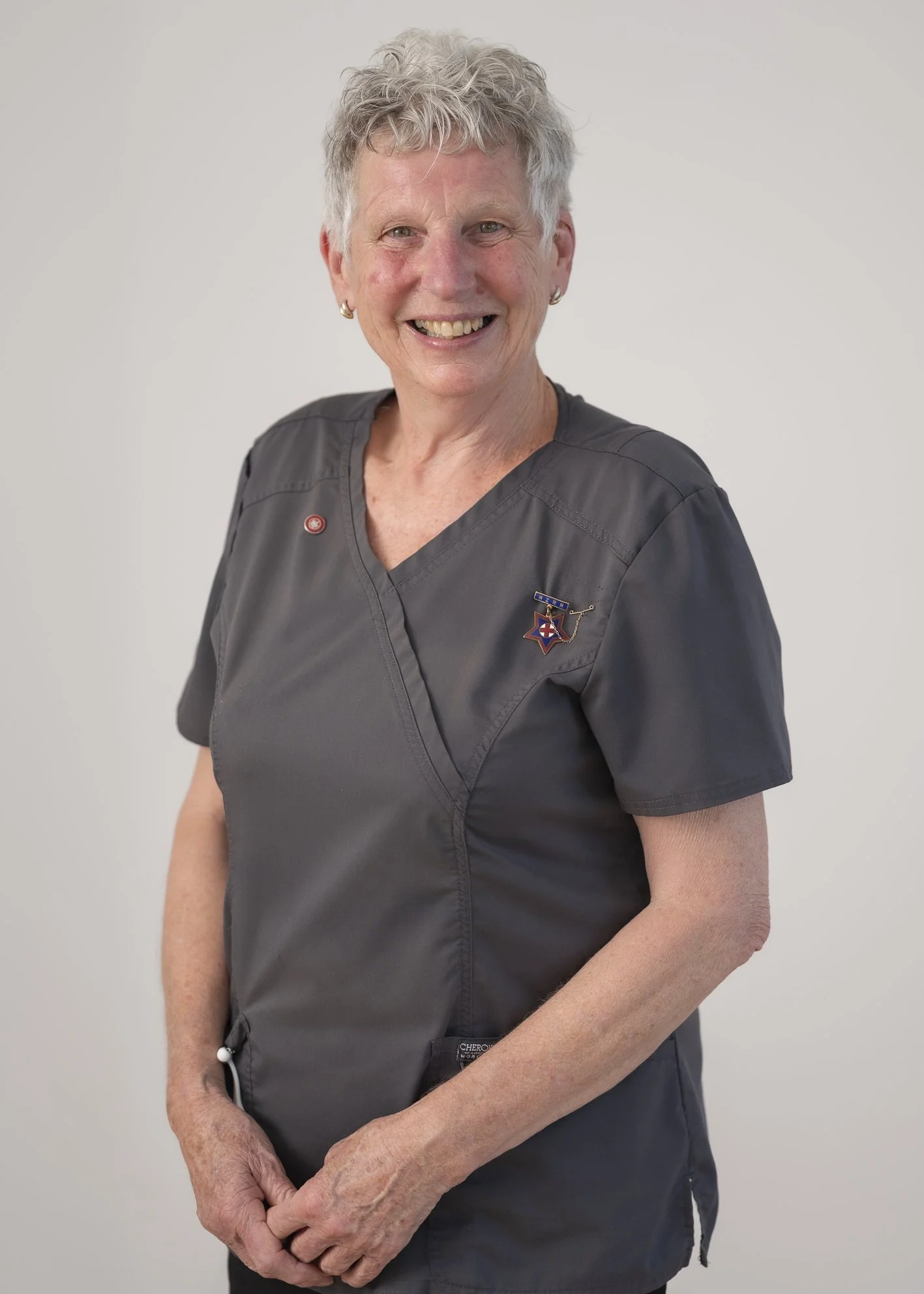 Portrait of Catriona Foster, Specialist Community Nurse, smiling warmly in clinical scrubs against a neutral background.