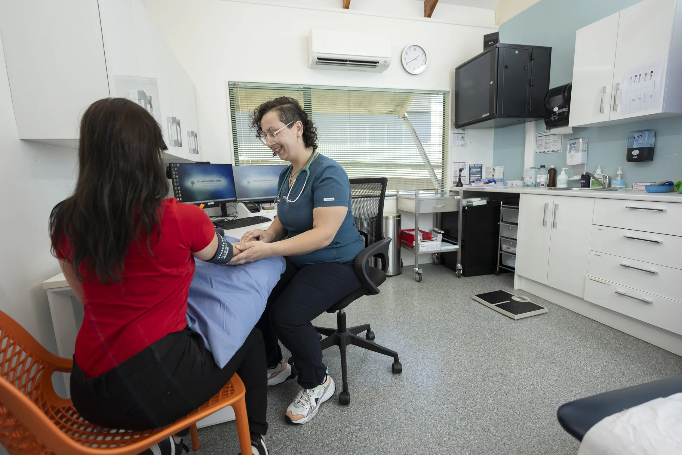 A healthcare professional taking the blood pressure of a woman in a medical examination room.