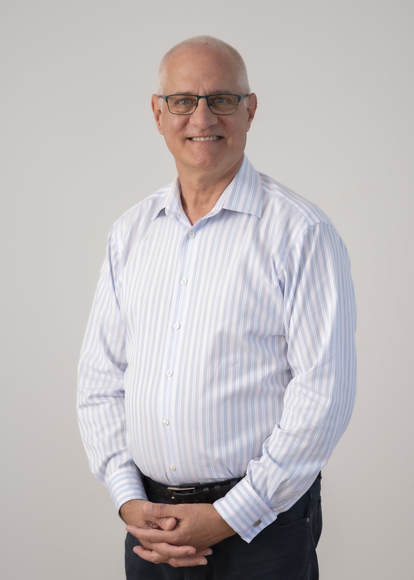Portrait of Dr Ed Schuck, Board Chair, standing against a neutral grey background.