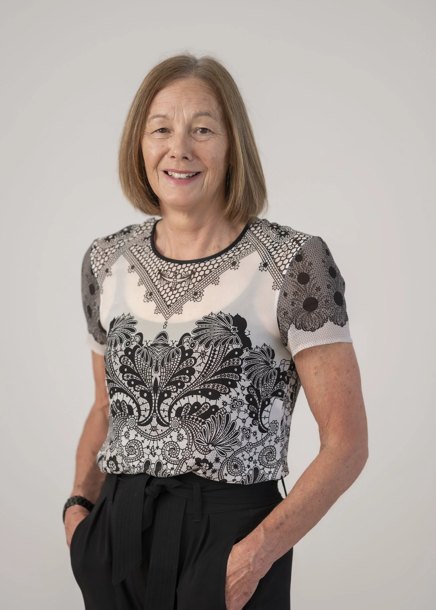 Portrait of Suzanne Wells, Medical Receptionist, smiling against a neutral grey background.